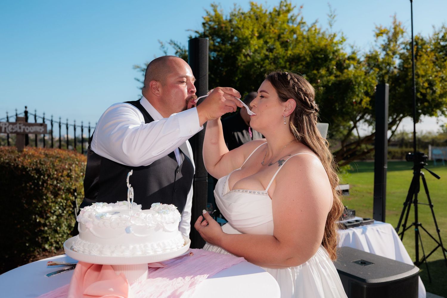 A couple shares a romantic moment during their wedding celebration in an outdoor garden setting.