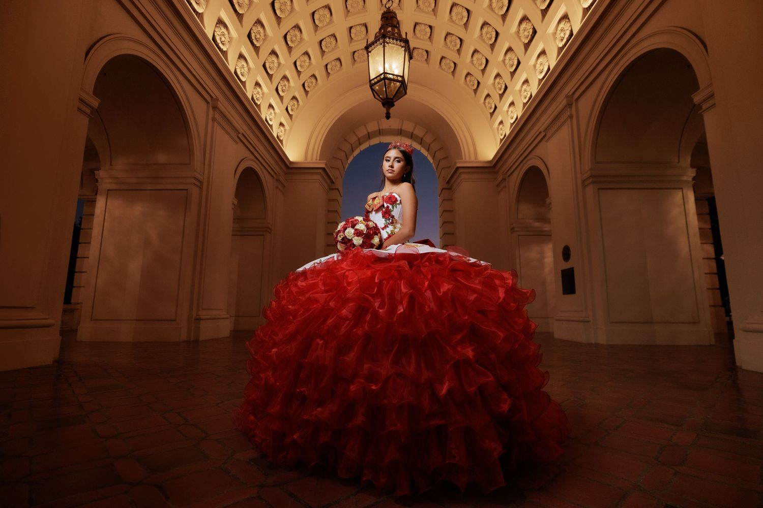Wedding photos in a grand hallway with ornate architecture and dramatic red dress details.