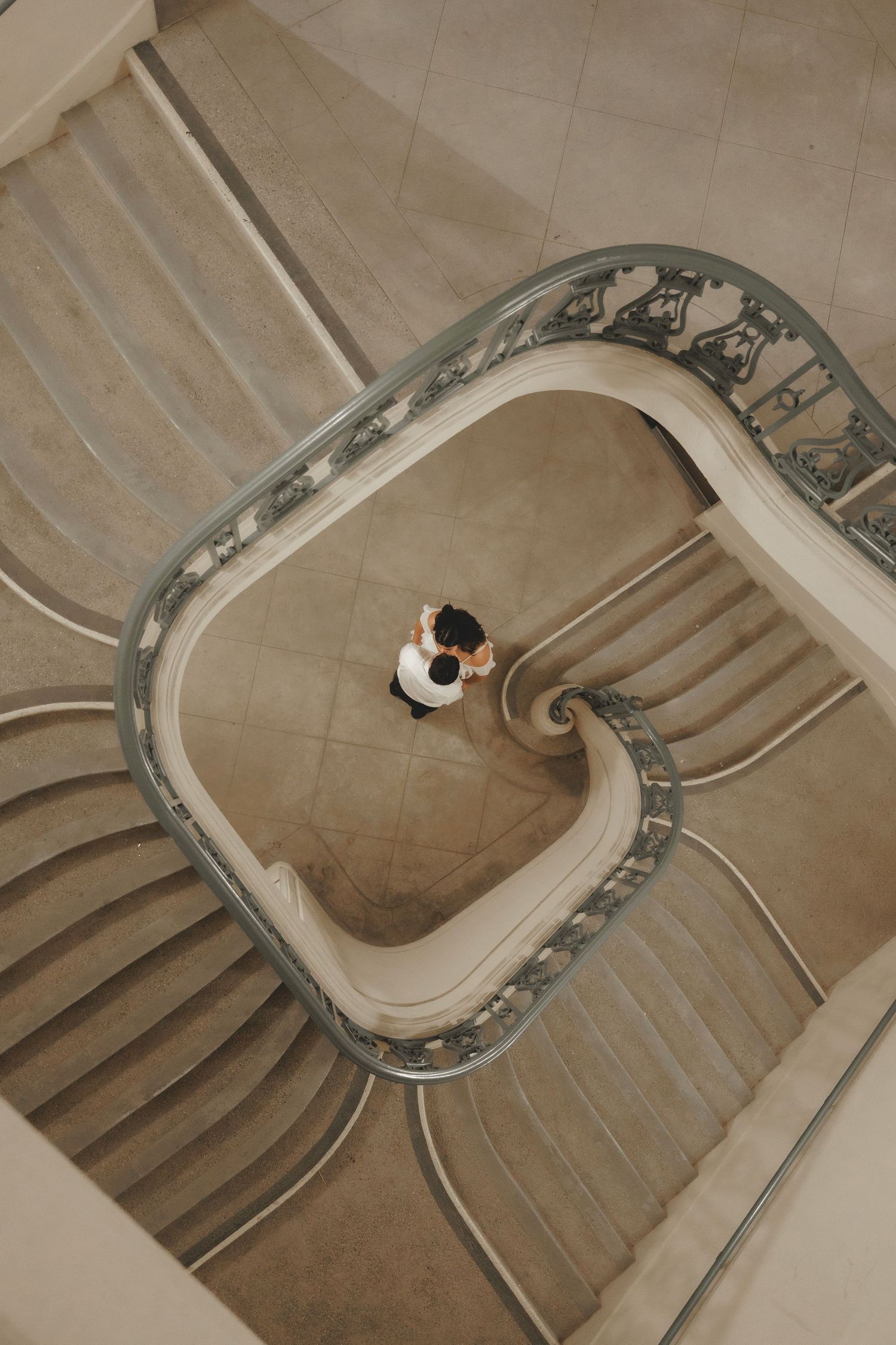 Stunning aerial view looking down a curved vintage staircase with ornate railings and marble steps.