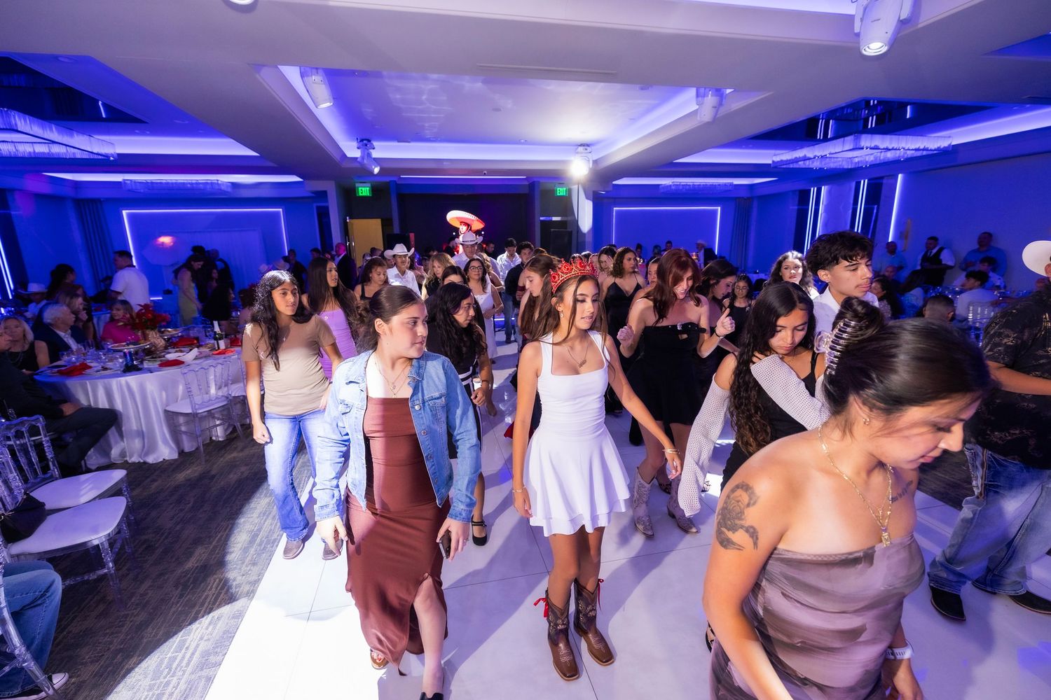 People dancing at a modern event venue with blue lighting and white decor creating a vibrant party atmosphere.