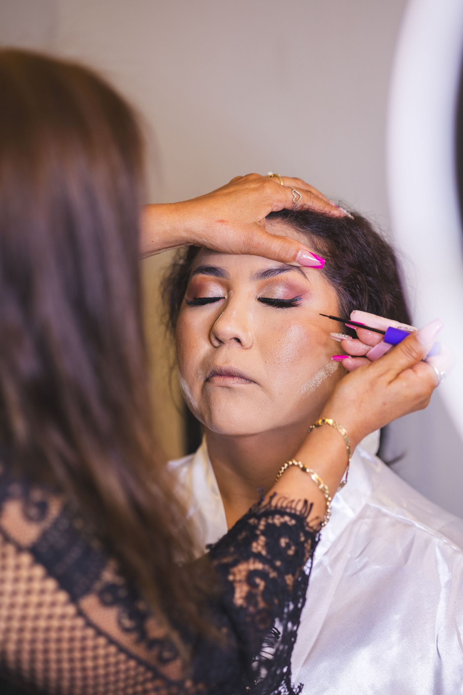 Professional makeup artist applying eye makeup and false lashes during a beauty session.