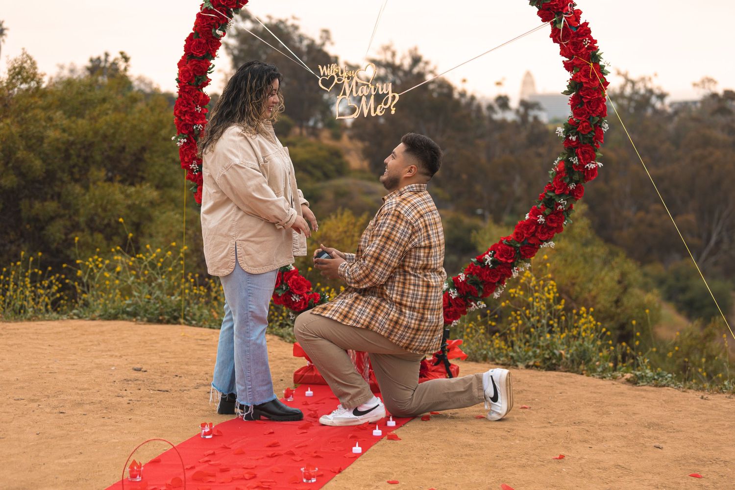 A red heart-shaped arch installation in an outdoor setting during golden hour.