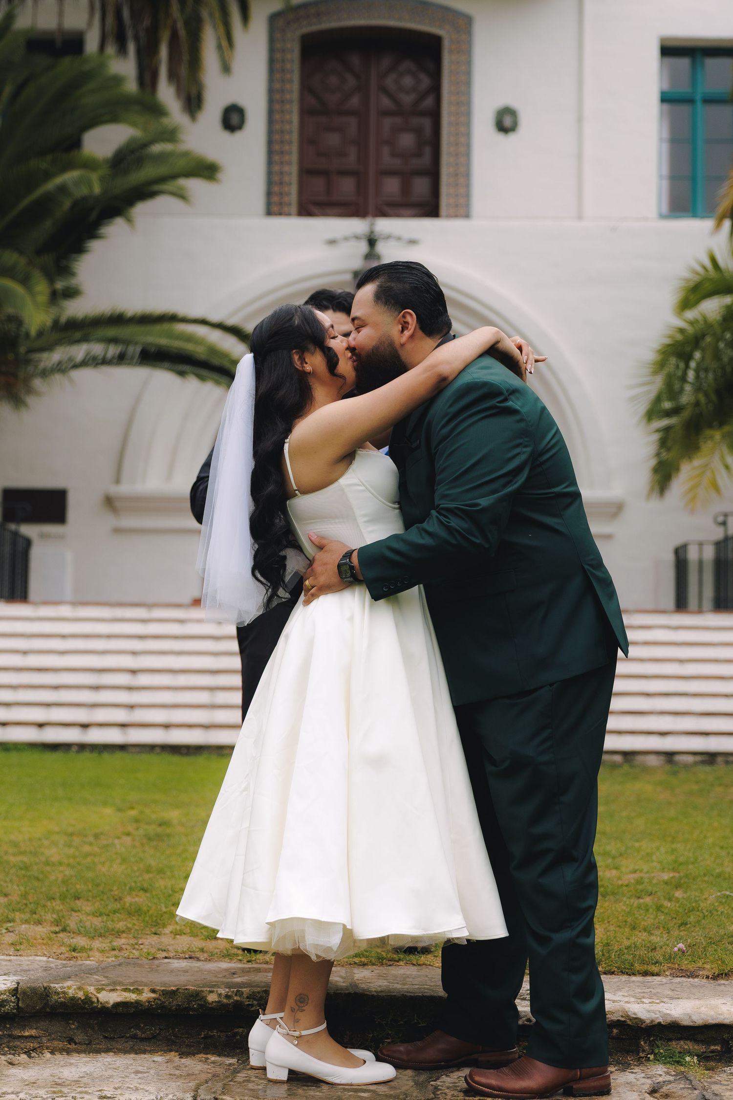 A couple shares romantic kisses in a sequence of photos outside a white building with palm trees.