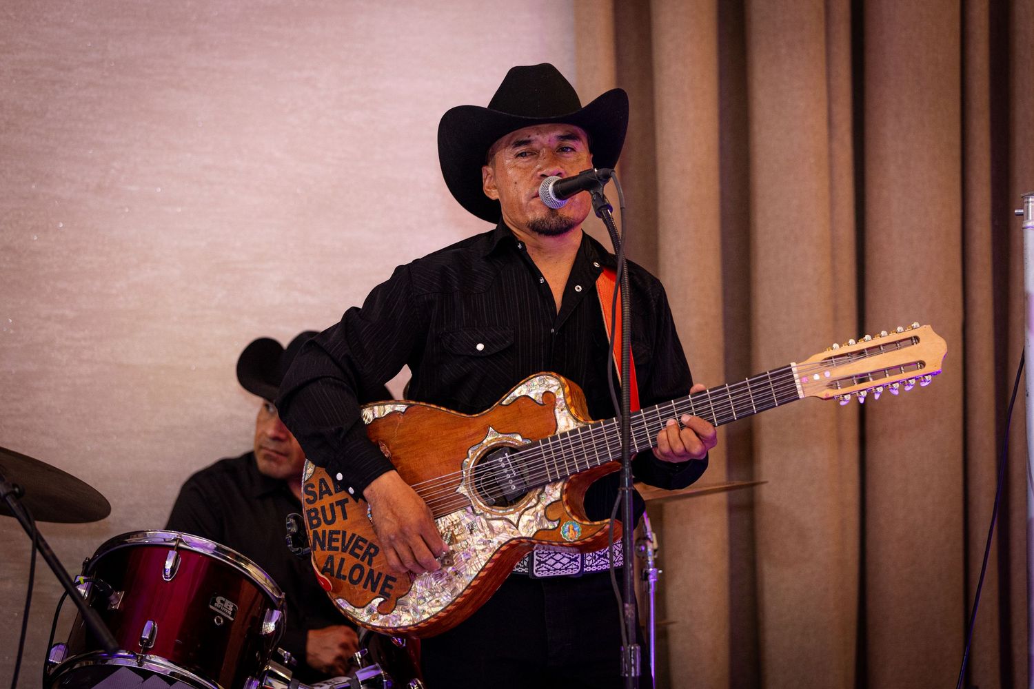 Musicians perform on stage with guitars and cowboy hats during a country music concert performance.