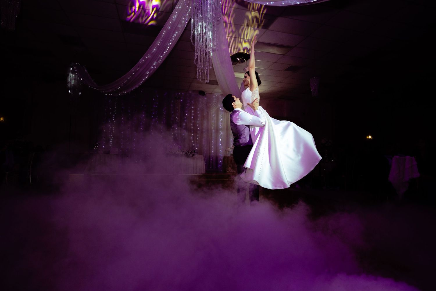 A couple performs an elegant dance lift in a purple-lit ballroom with atmospheric fog effects.