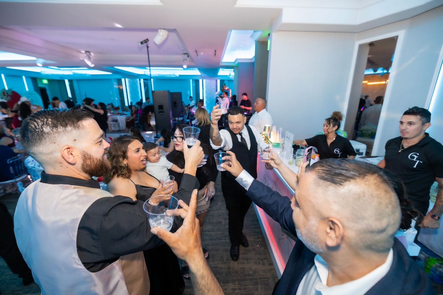 Party guests raise their drinks in a celebratory toast during a festive indoor gathering.