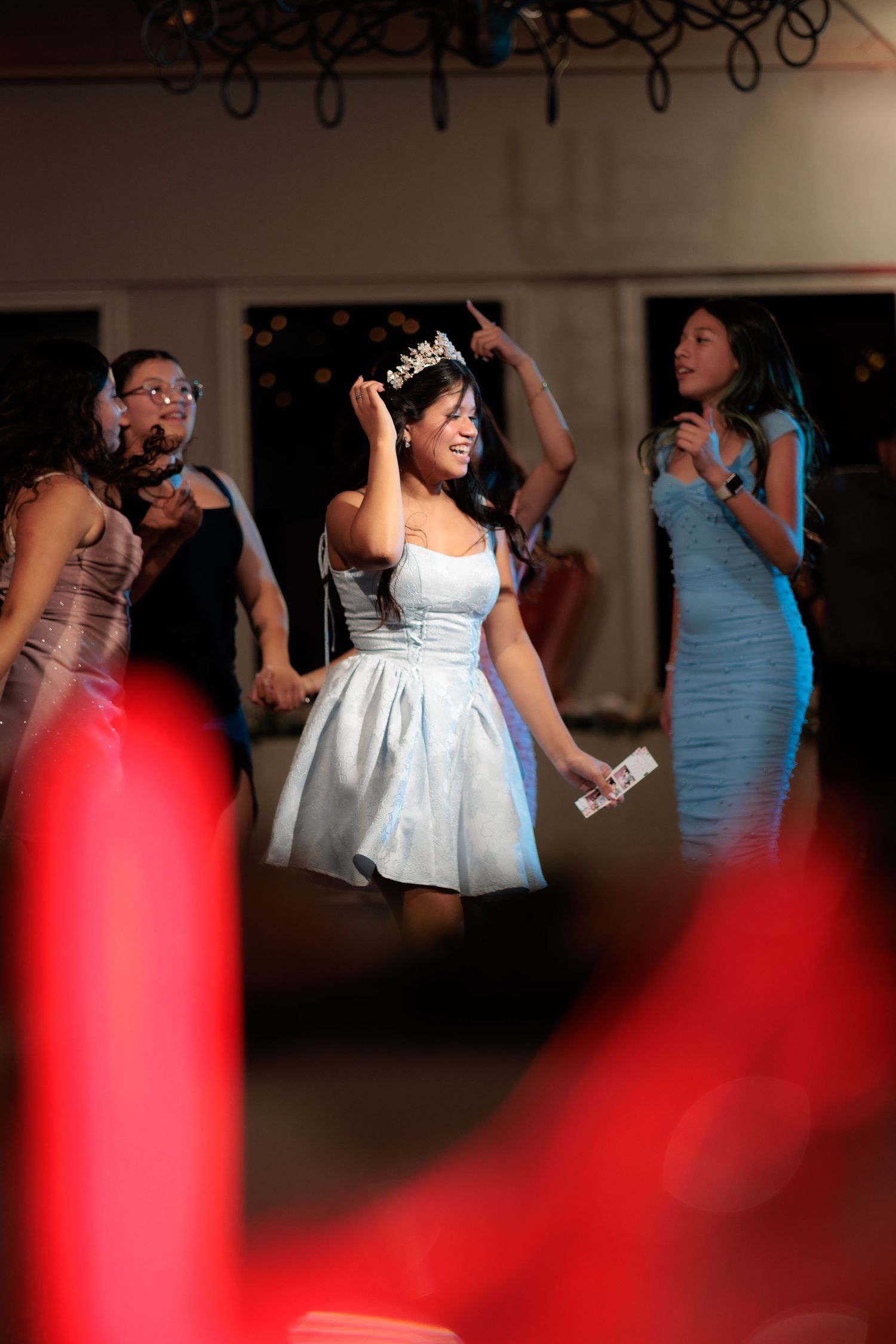 People dancing and celebrating at a wedding reception with a red light effect in the foreground.