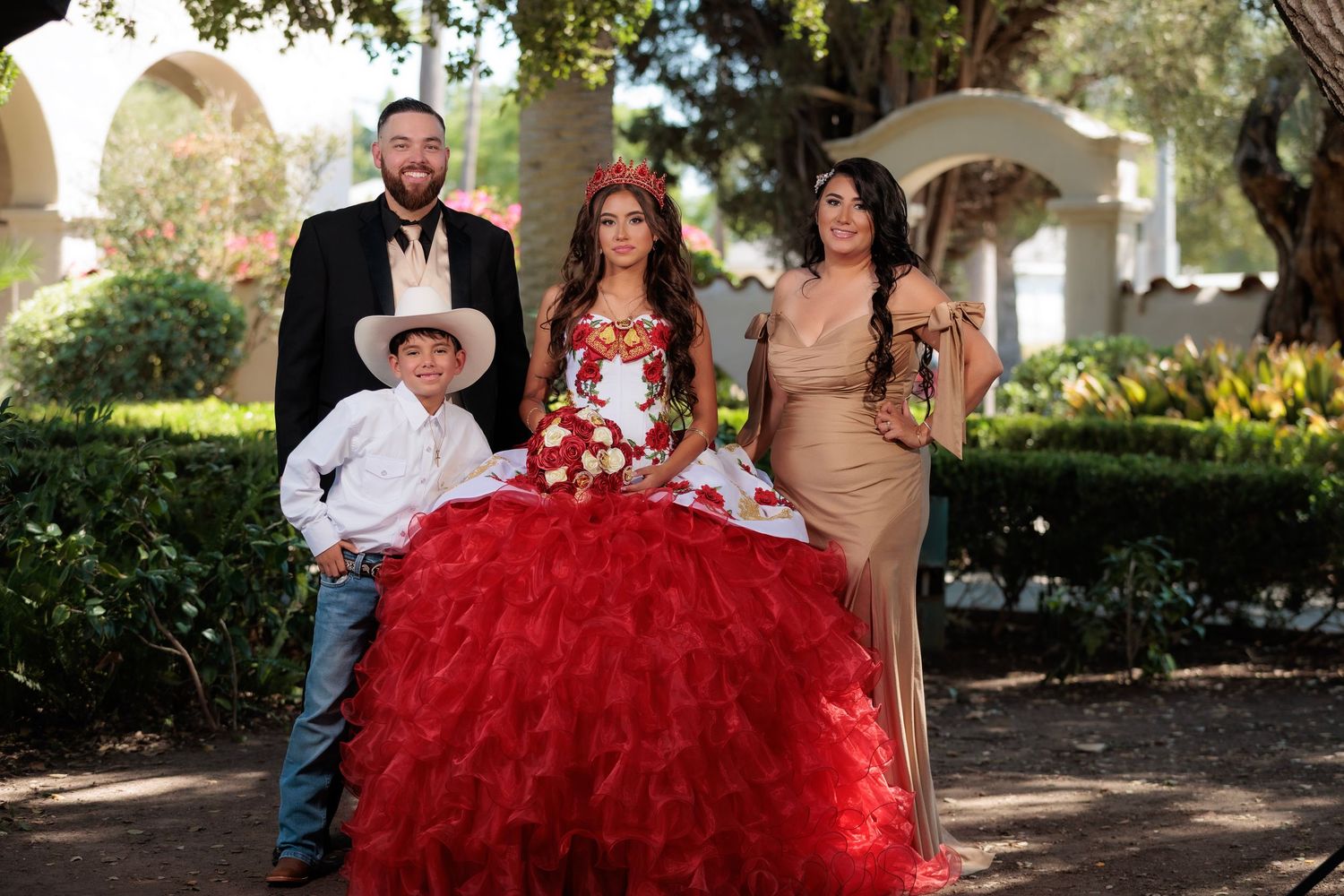 A group celebrates at an outdoor quinceañera event with a stunning red ball gown as the centerpiece.