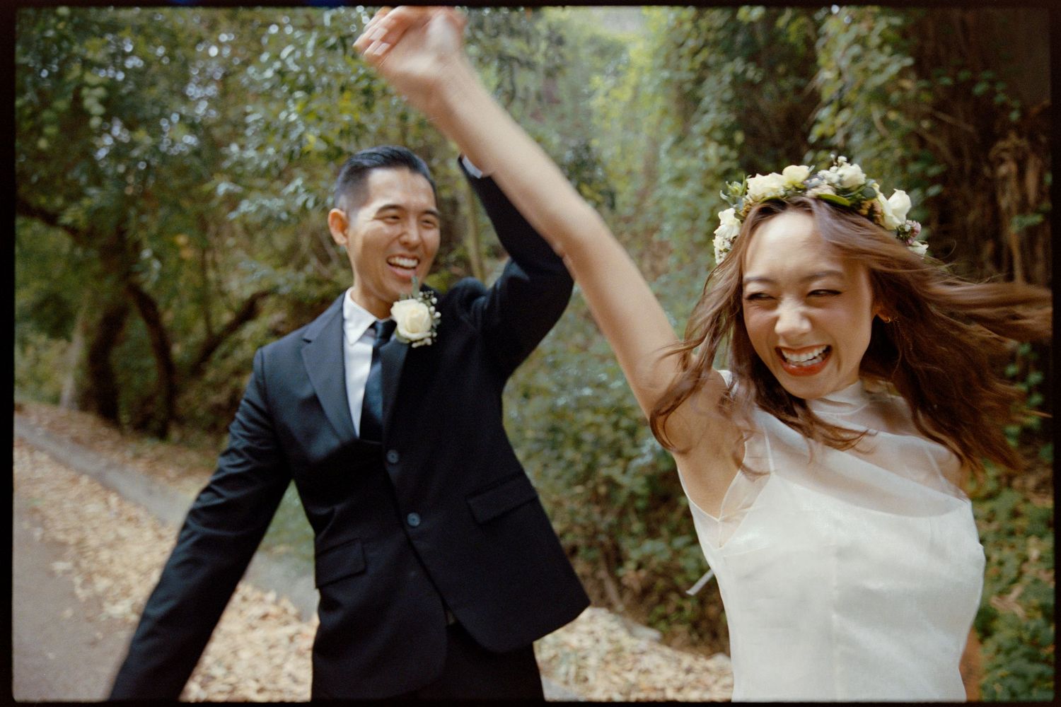 A couple shares joyful moments during their outdoor wedding celebration in a wooded setting.