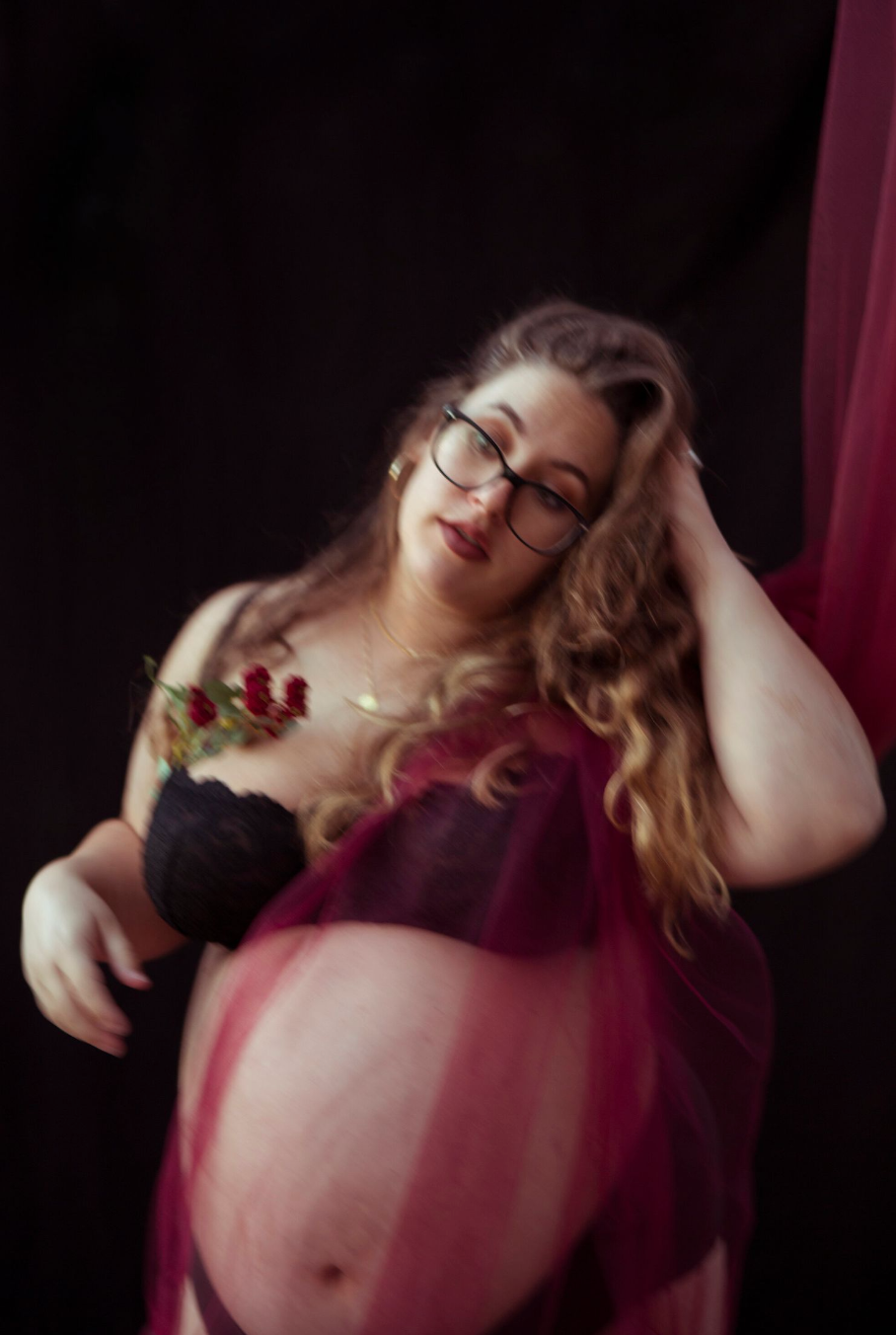 A maternity portrait with red berries against burgundy fabric creates a romantic atmosphere.
