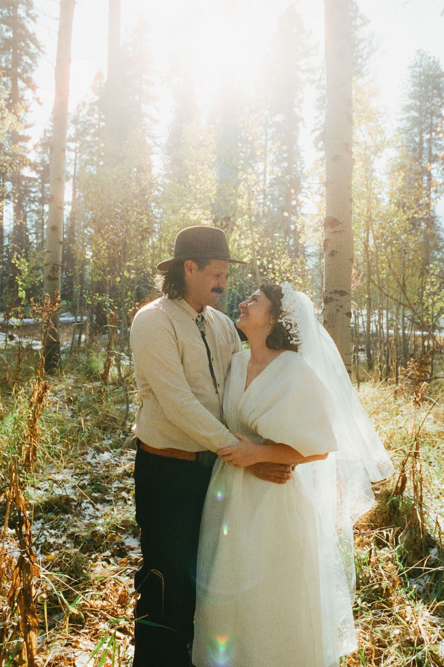 A sunlit forest wedding scene with golden light streaming through tall pine trees.