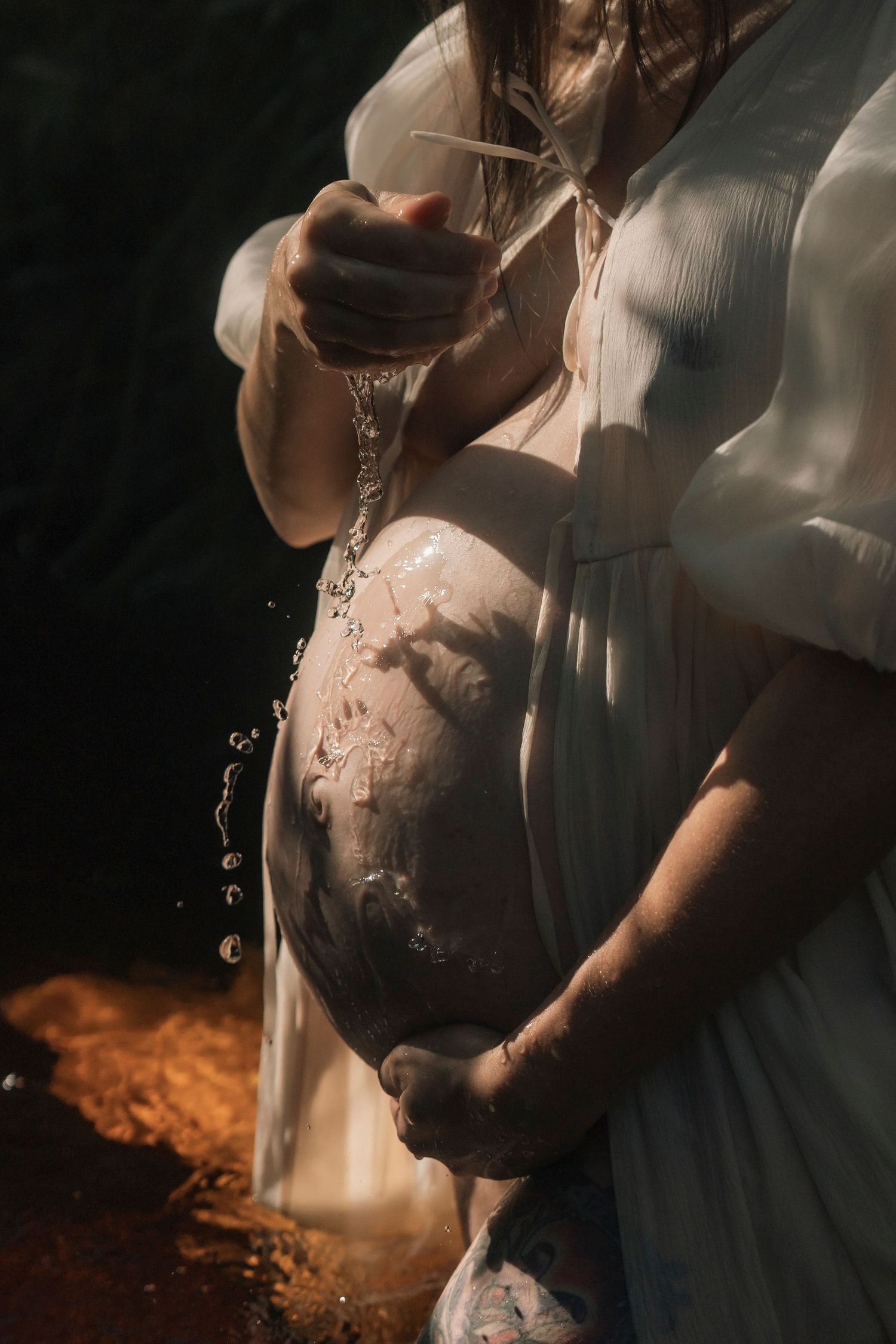 A dramatic series of maternity photos showing a pregnant belly in white dress with smoke effects and moody lighting.