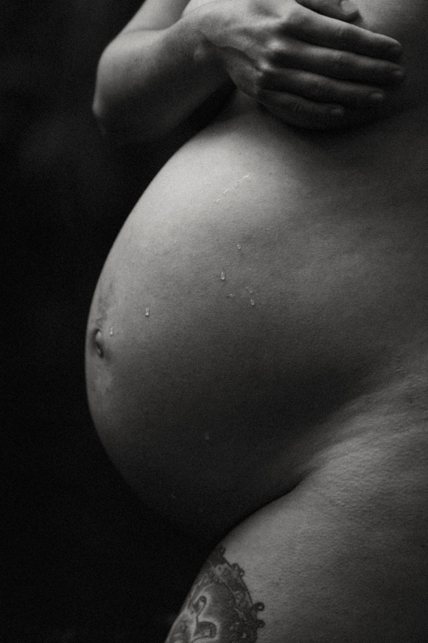A series of black and white photographs showing a pregnant belly with a henna design in progressive stages of pregnancy.