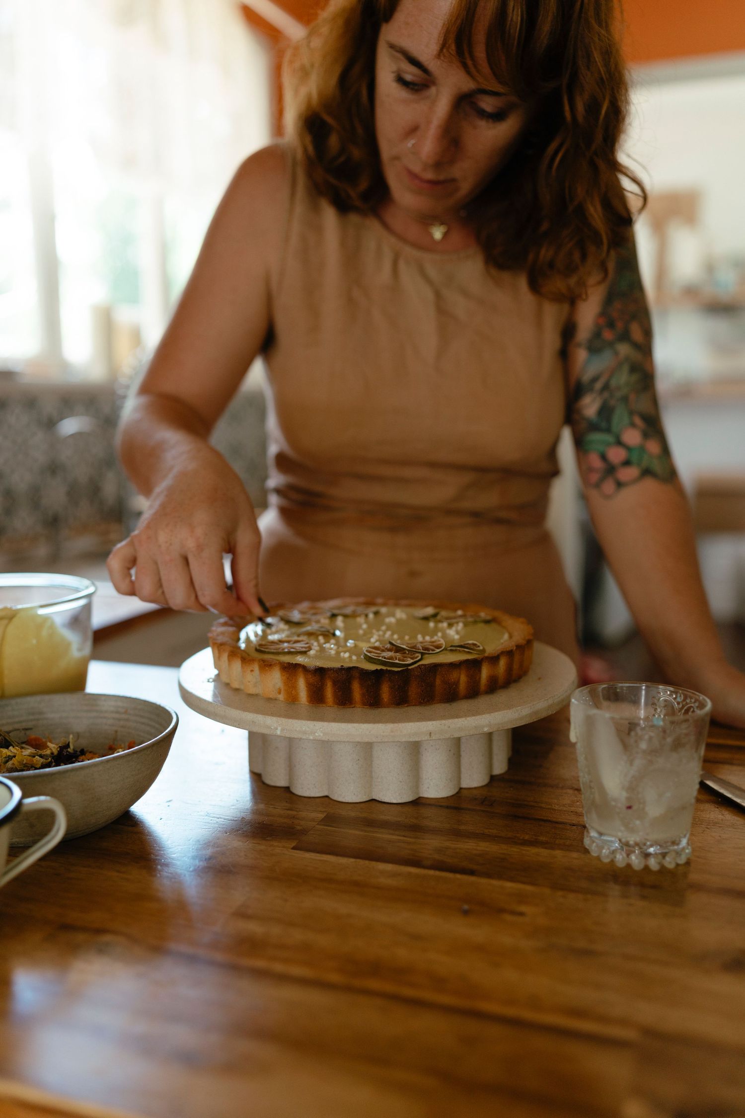 Someone with tattooed arm works on assembling a dessert while sitting at a wooden table. personal brand photography