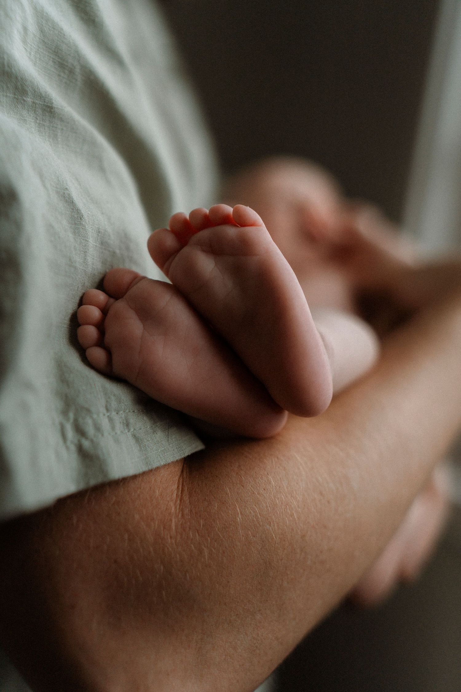 Close-up sequence showing tiny baby feet resting against a soft white fabric in warm, natural lighting.