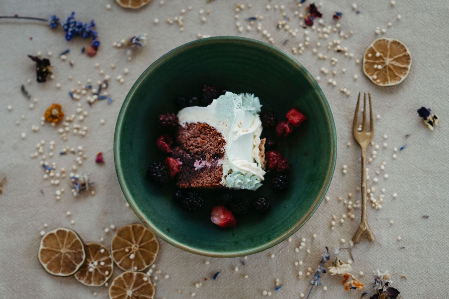 Chocolate dessert with whipped cream served in a green bowl with dried citrus and holiday decorations scattered around.