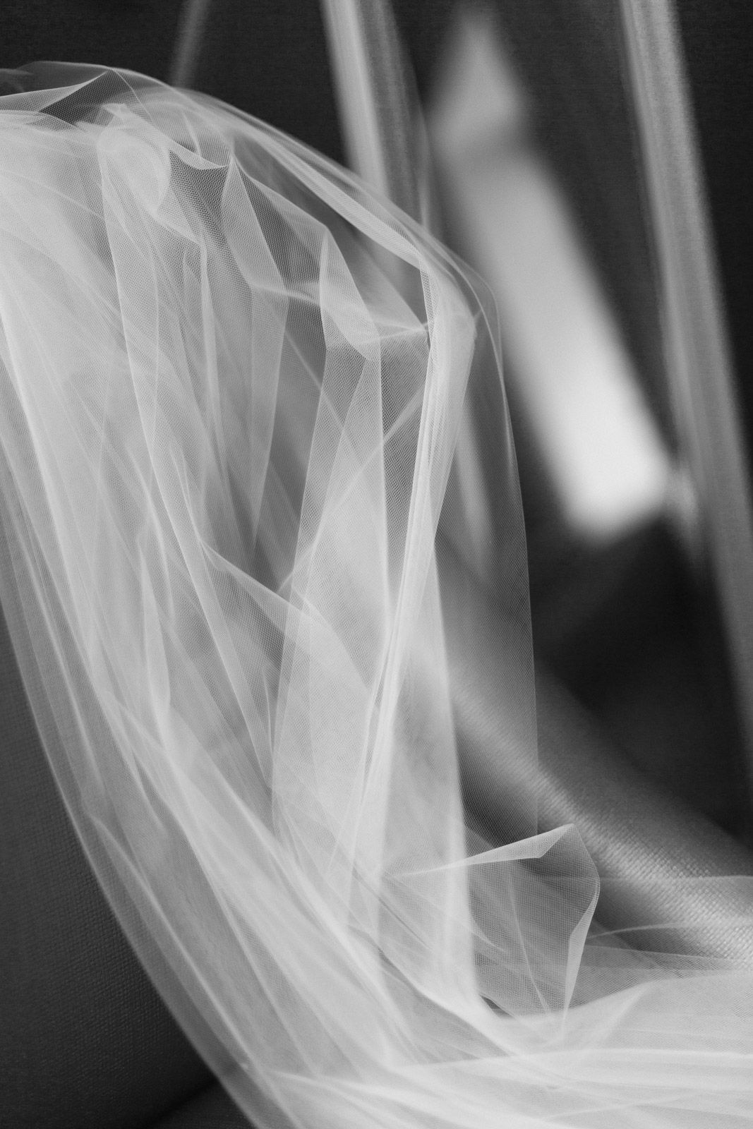 Black and white close-up of delicate white tulle fabric draped elegantly, showcasing soft folds and sheer texture.