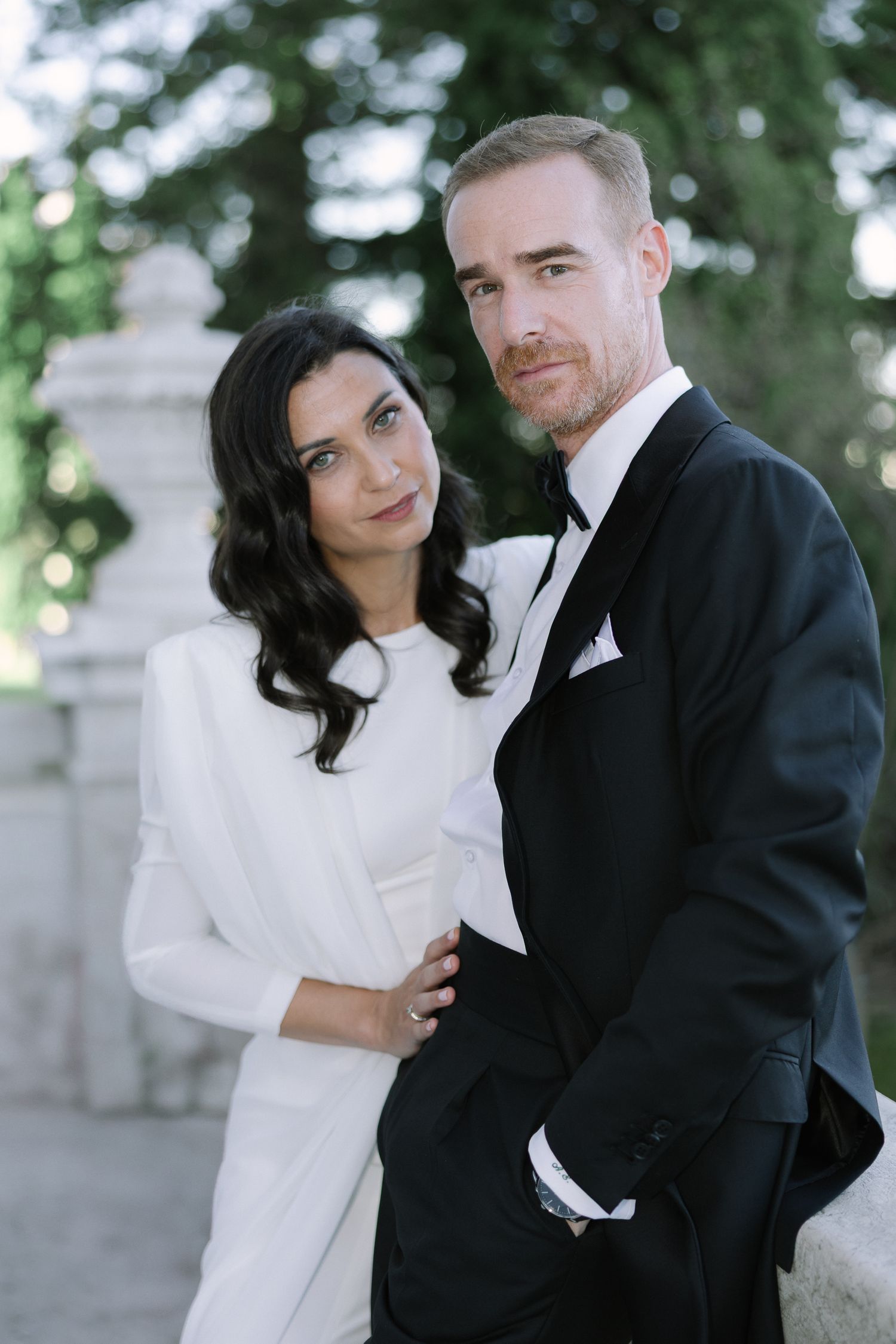A couple in formal wedding attire poses together during a romantic outdoor photo session.