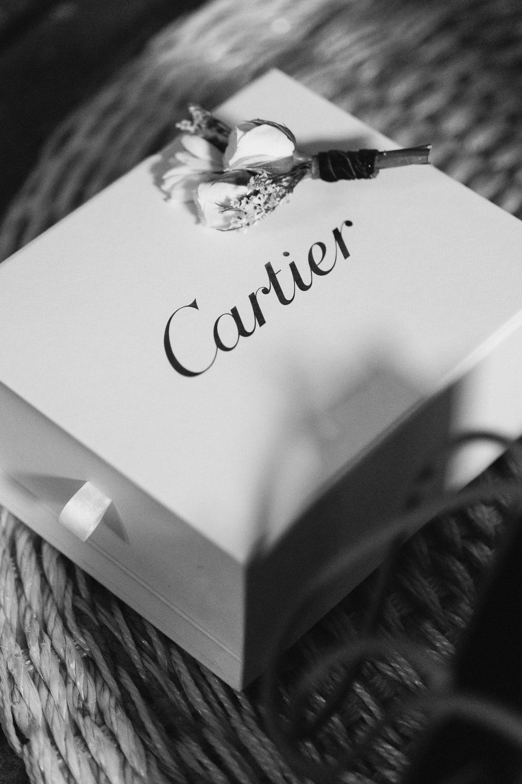 Black and white photo of a Cartier gift box with a diamond ring and car key on top.