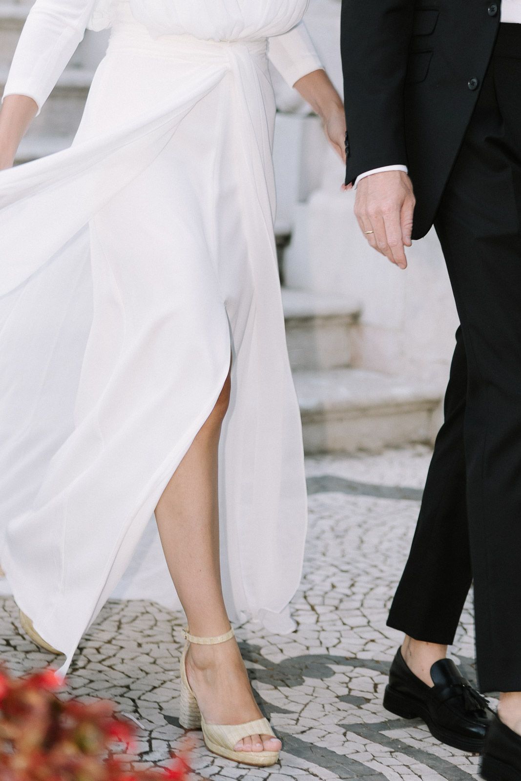 Bride in white wedding dress with slit and block heel sandals walking with groom.