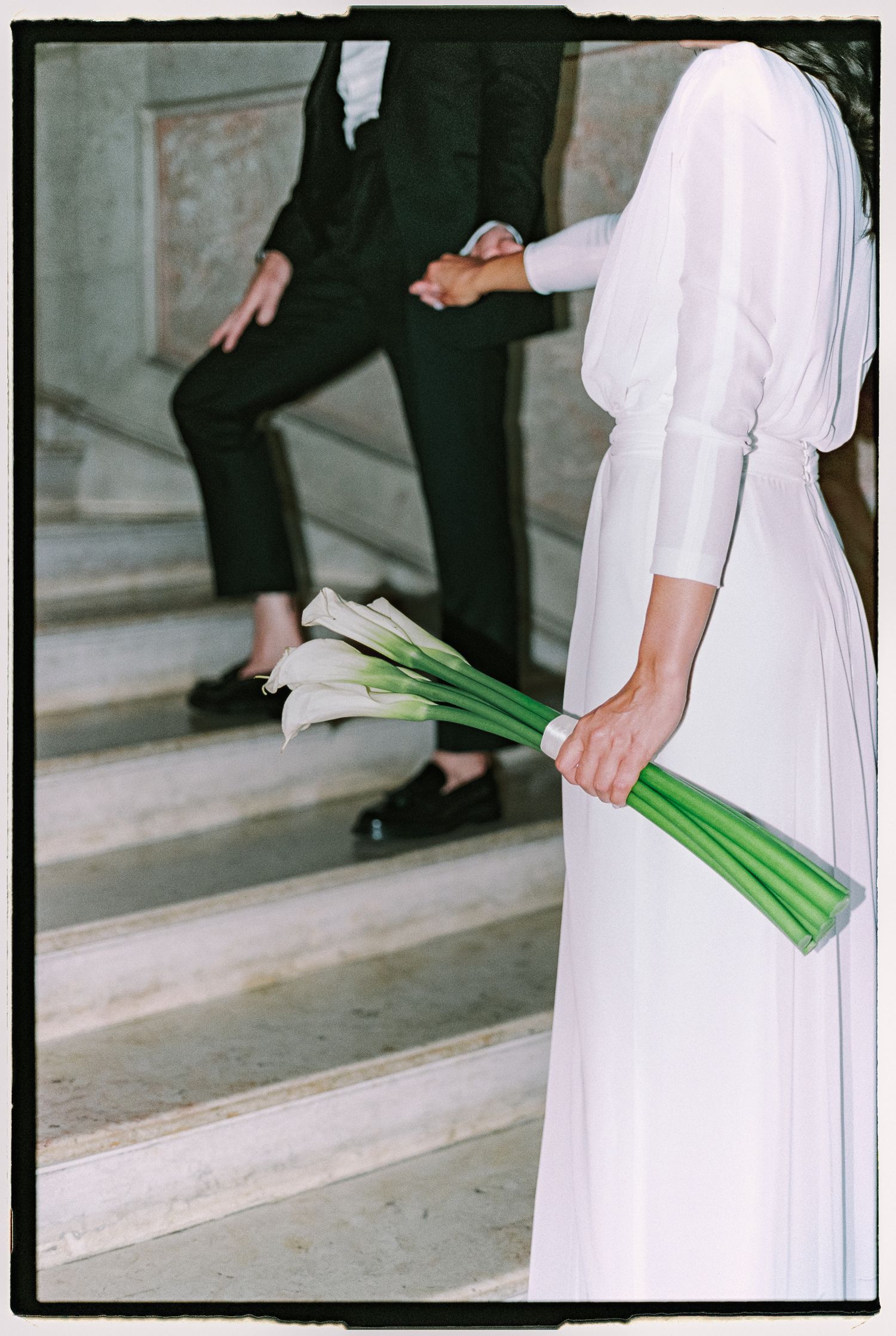 A series of photos showing a person in white clothing walking down concrete steps while carrying green elongated objects.