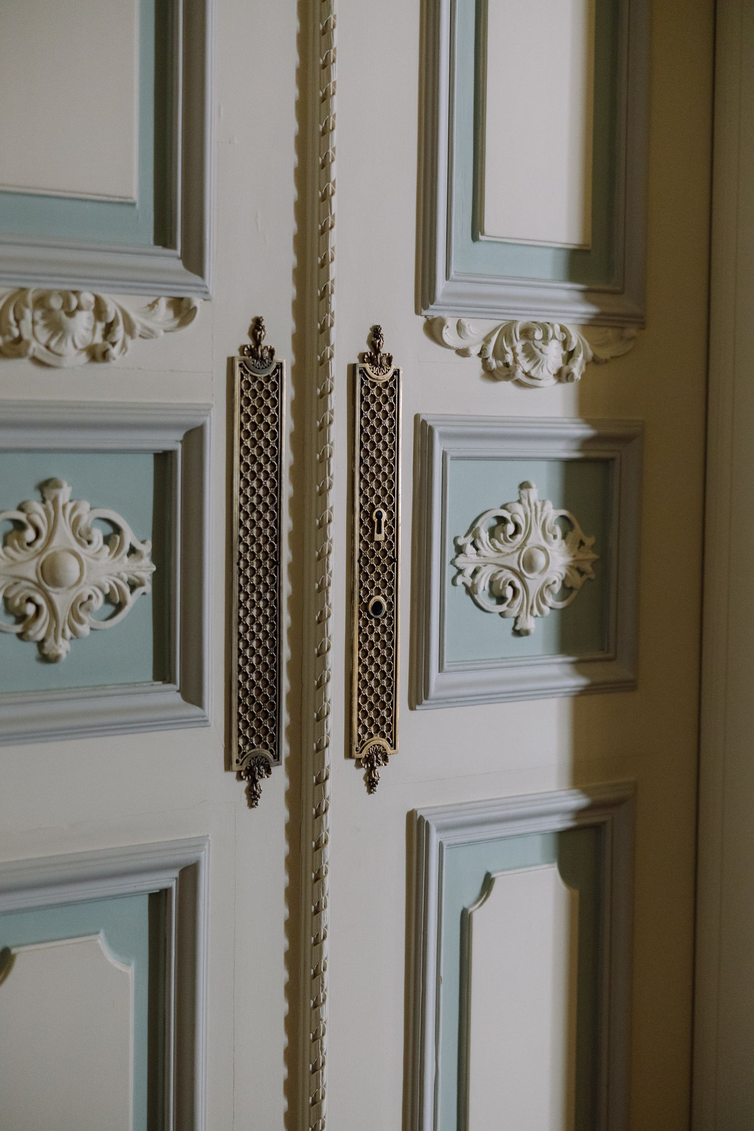 Ornate white wall paneling with decorative moldings and lattice details showcases elegant Victorian architectural style.