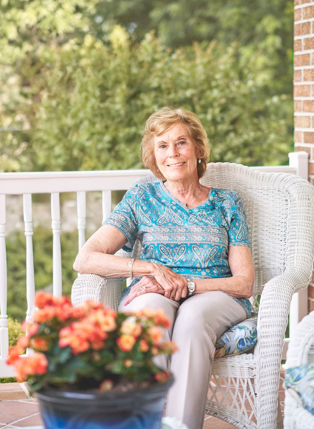 Elderly woman seated on white wicker chair on her Perry Hall MD front porch