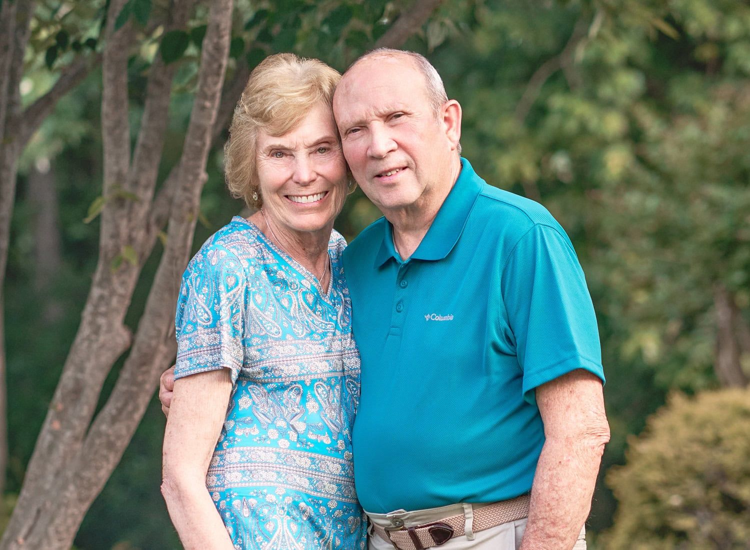 Elderly couple cheek-to-cheek standing in their front Perry Hall MD yard