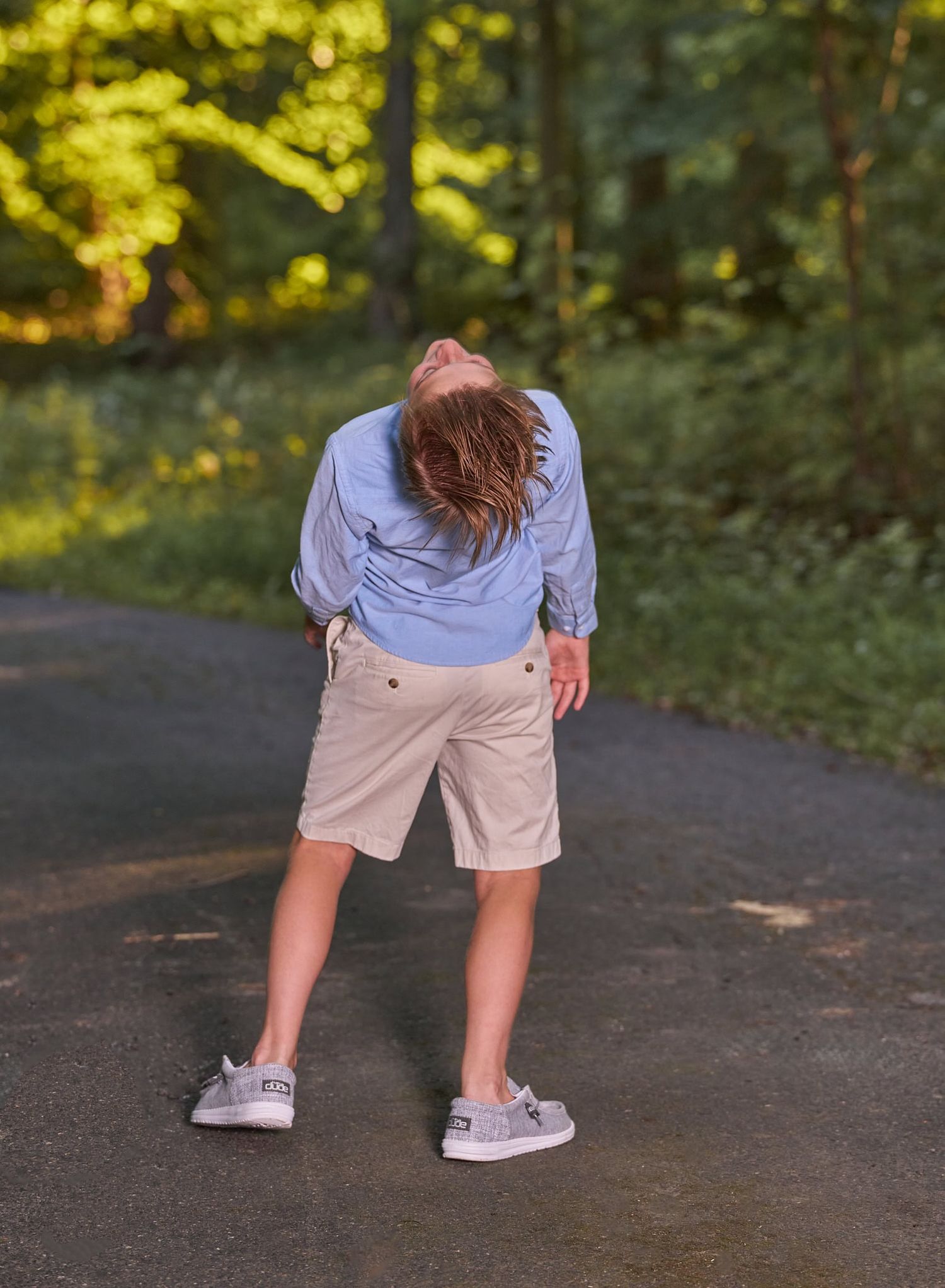Mischievous 12-year-old boy in a backwards pose throwing his head back