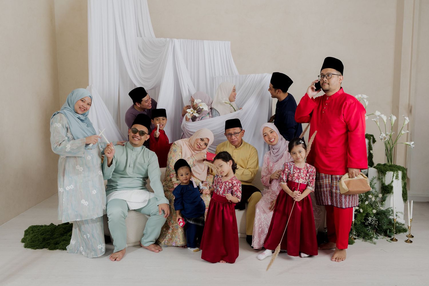 A large Malaysian family poses together in traditional Eid attire for a festive portrait photo.
