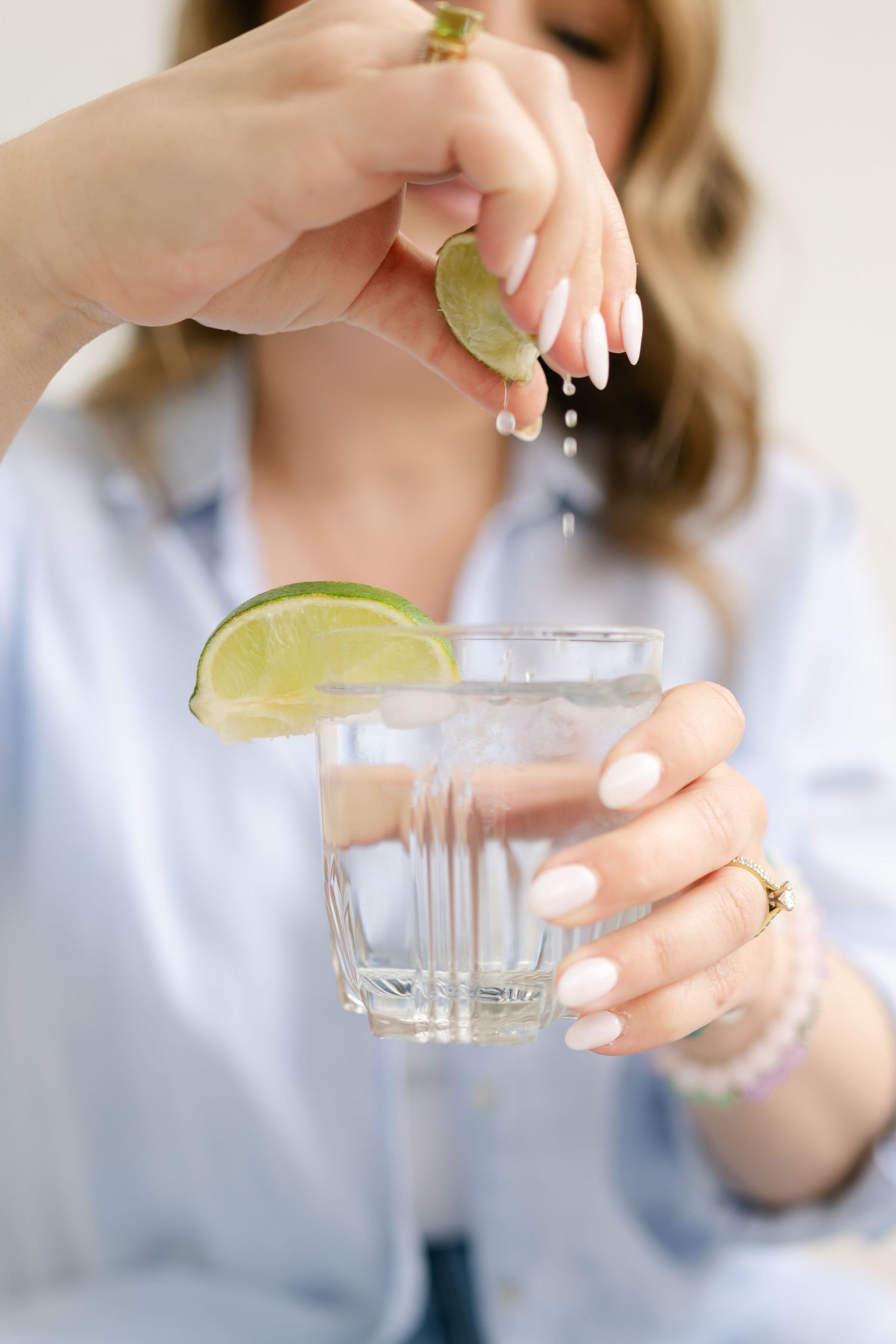 A pair of hands squeezes fresh lime juice into a clear glass in a sequential photo series.