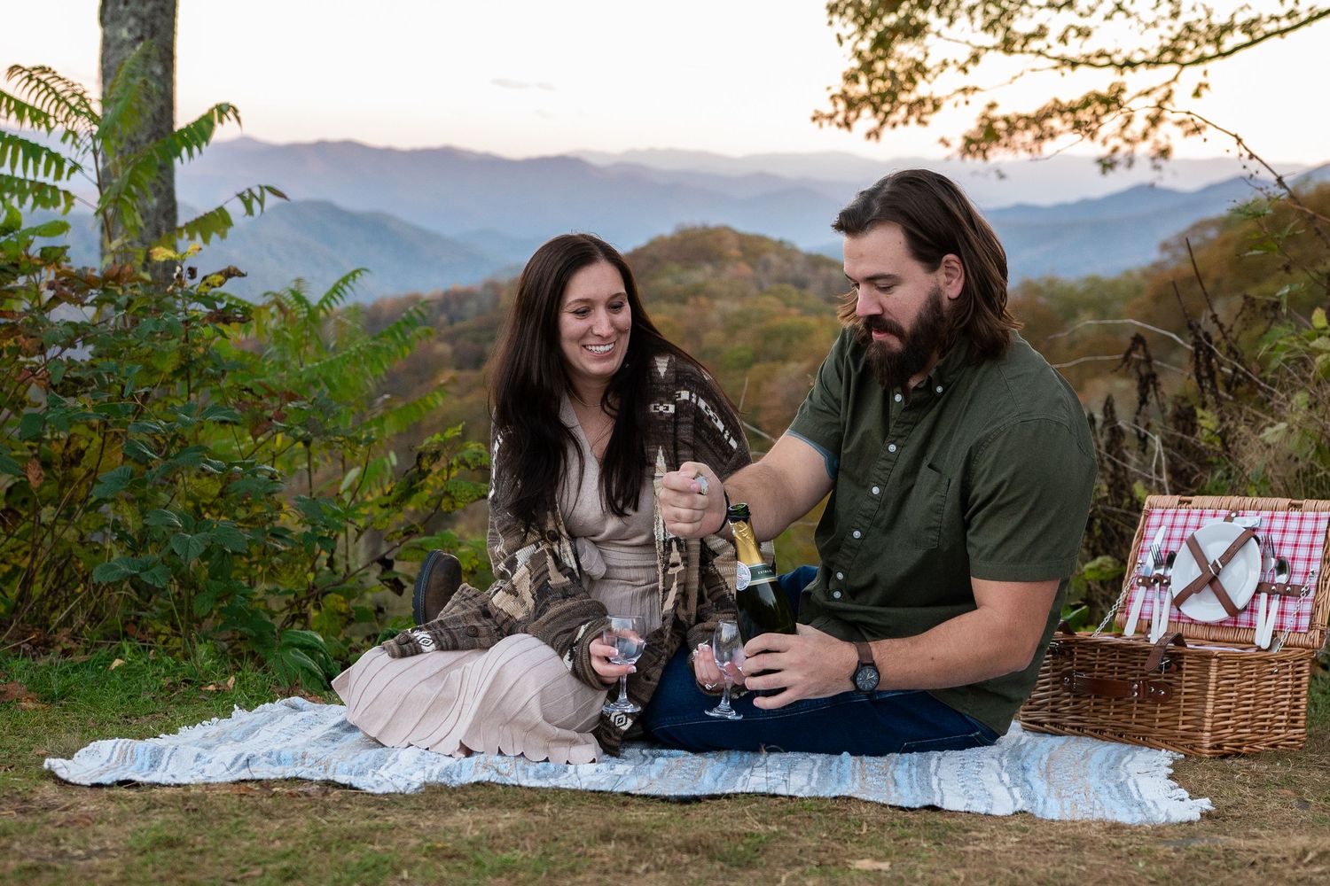 Couple sharing wine at a mountain overlook picnic with scenic blue ridge mountain views in autumn.