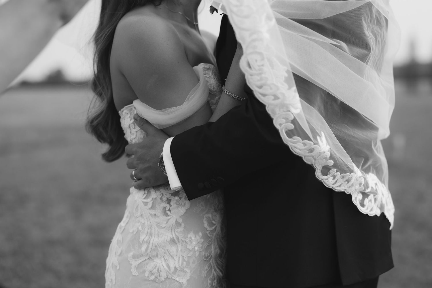 Cotswolds wedding photographer captures bride and groom with a flowing white lace wedding veil in the breeze.
