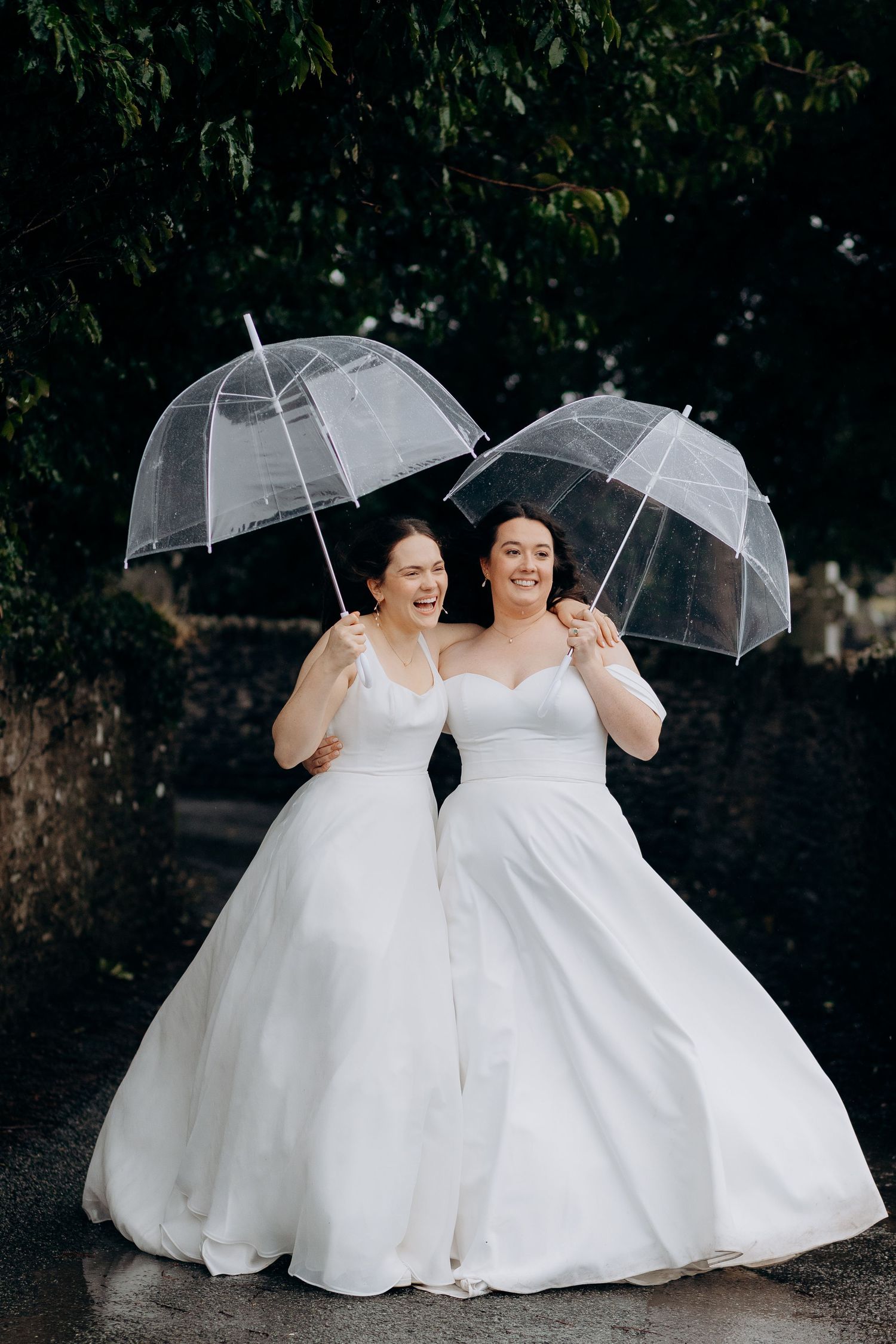 Two brides in wedding dresses having fun on their wedding day in the cotswolds.