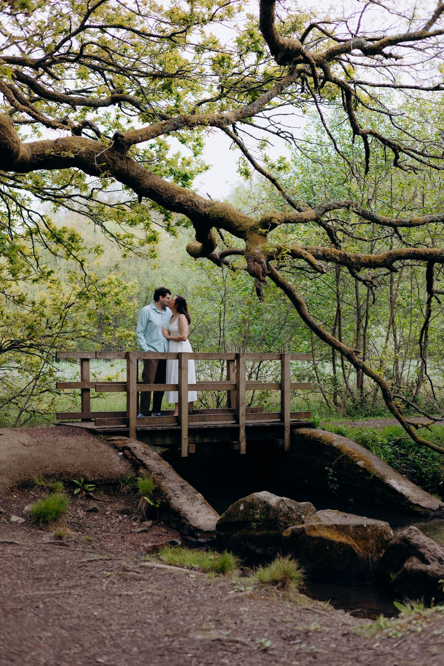 Pre wedding photography session in Forest of Dean capturing engaged couple walking hand in hand through woodland paths.