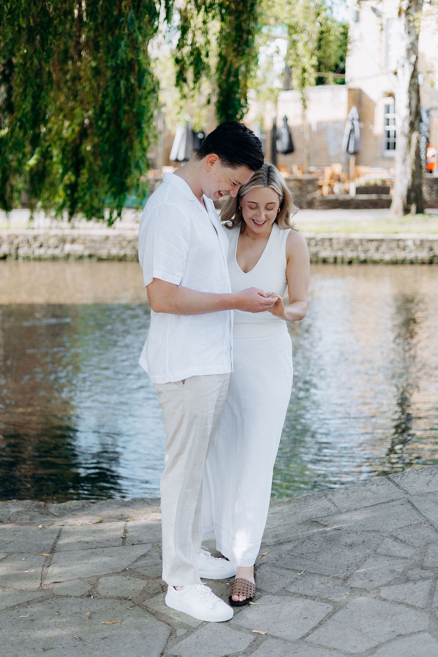 Surprise proposal in Bourton-on-the-Water with newly engaged couple celebrating.