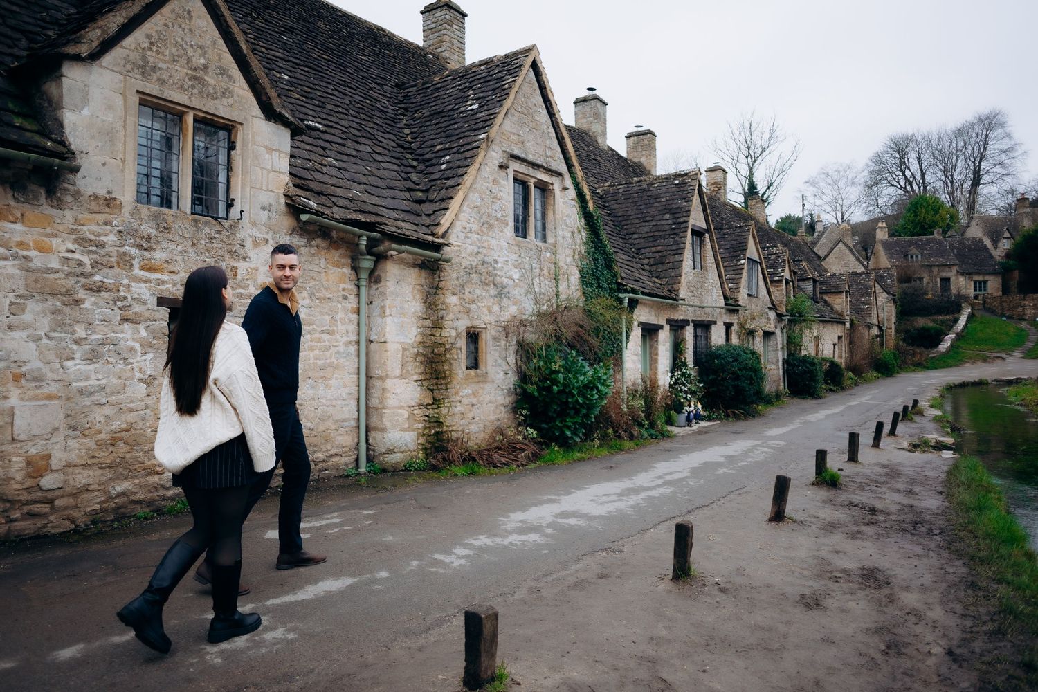 A series of black and white photos showing people walking along a quaint stone-lined village street in the Cotswolds.