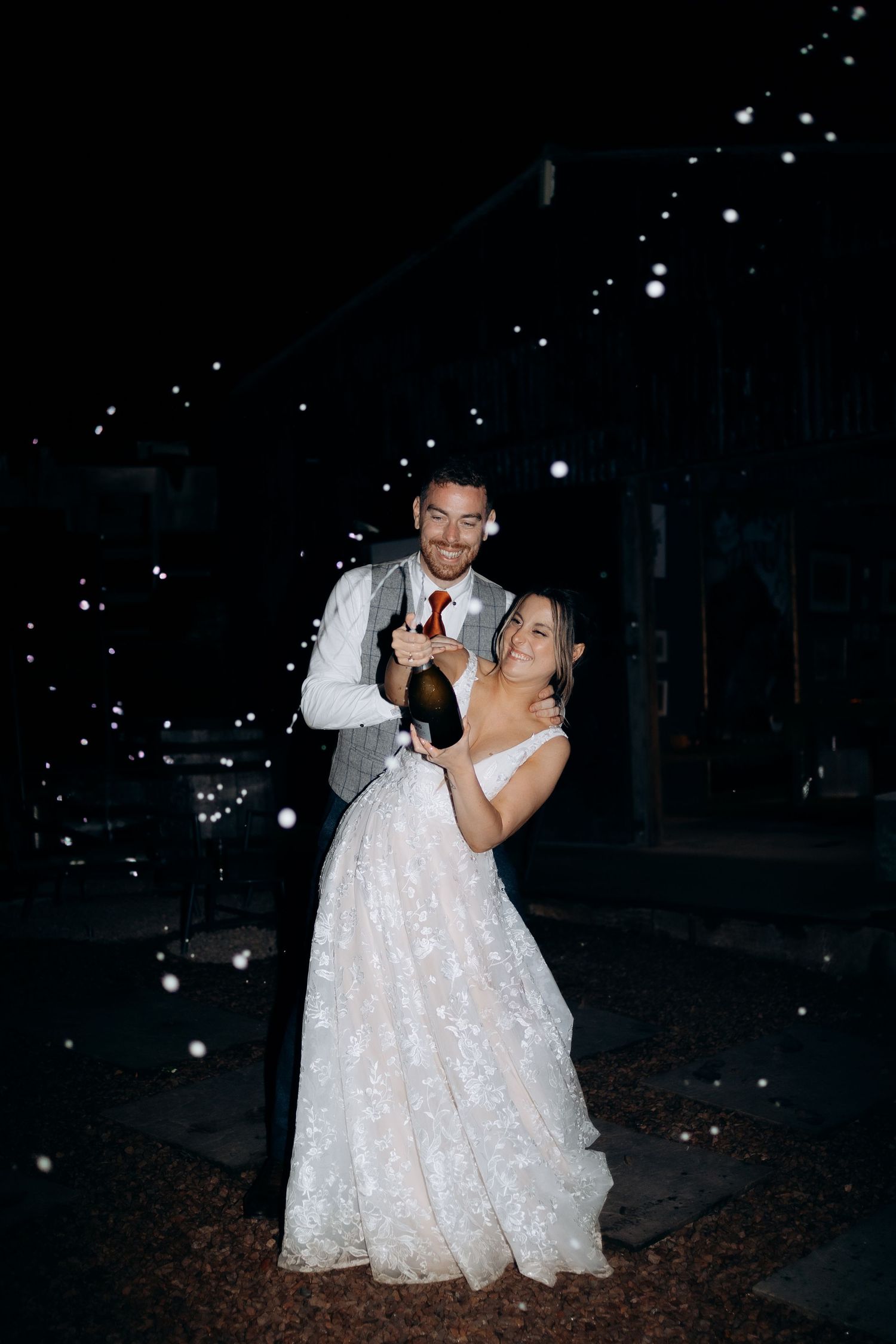 A bride and groom share a romantic nighttime moment outdoors captured by a cotswolds wedding photographer.
