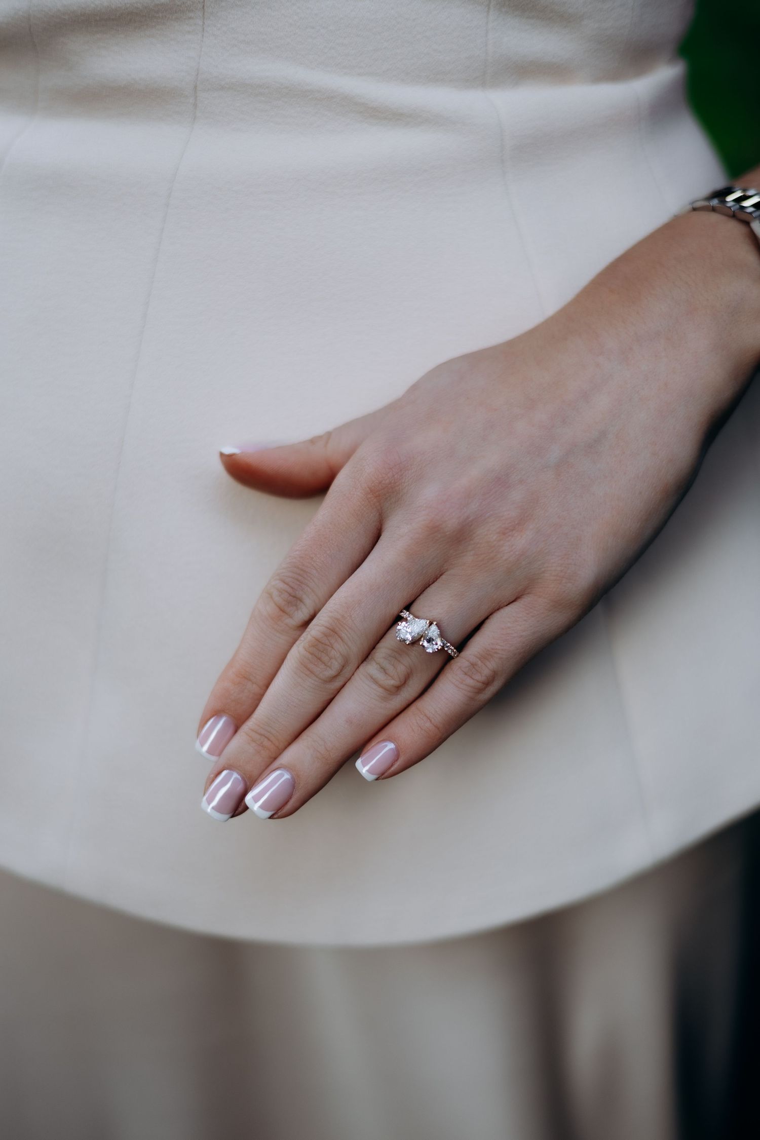 Close up view of a hand wearing an elegant solitaire diamond engagement ring on a white fabric background in the Cotswolds.