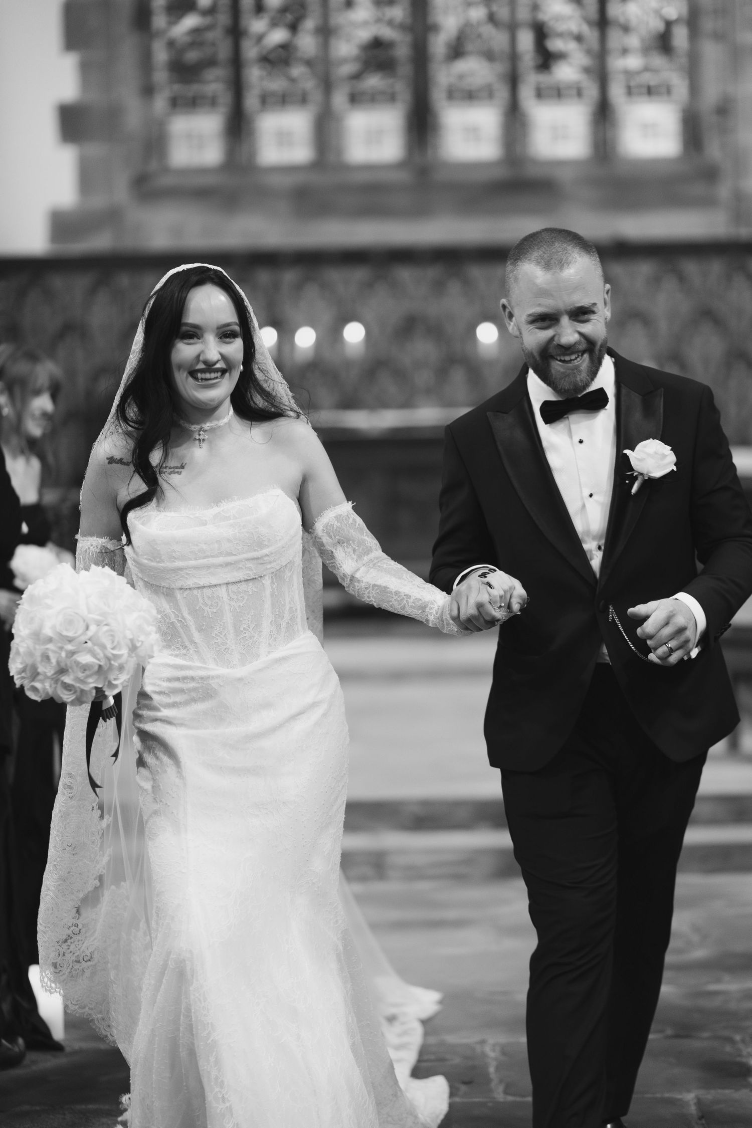Black and white photo of a smiling bride and groom walking down the aisle after their church wedding ceremony.