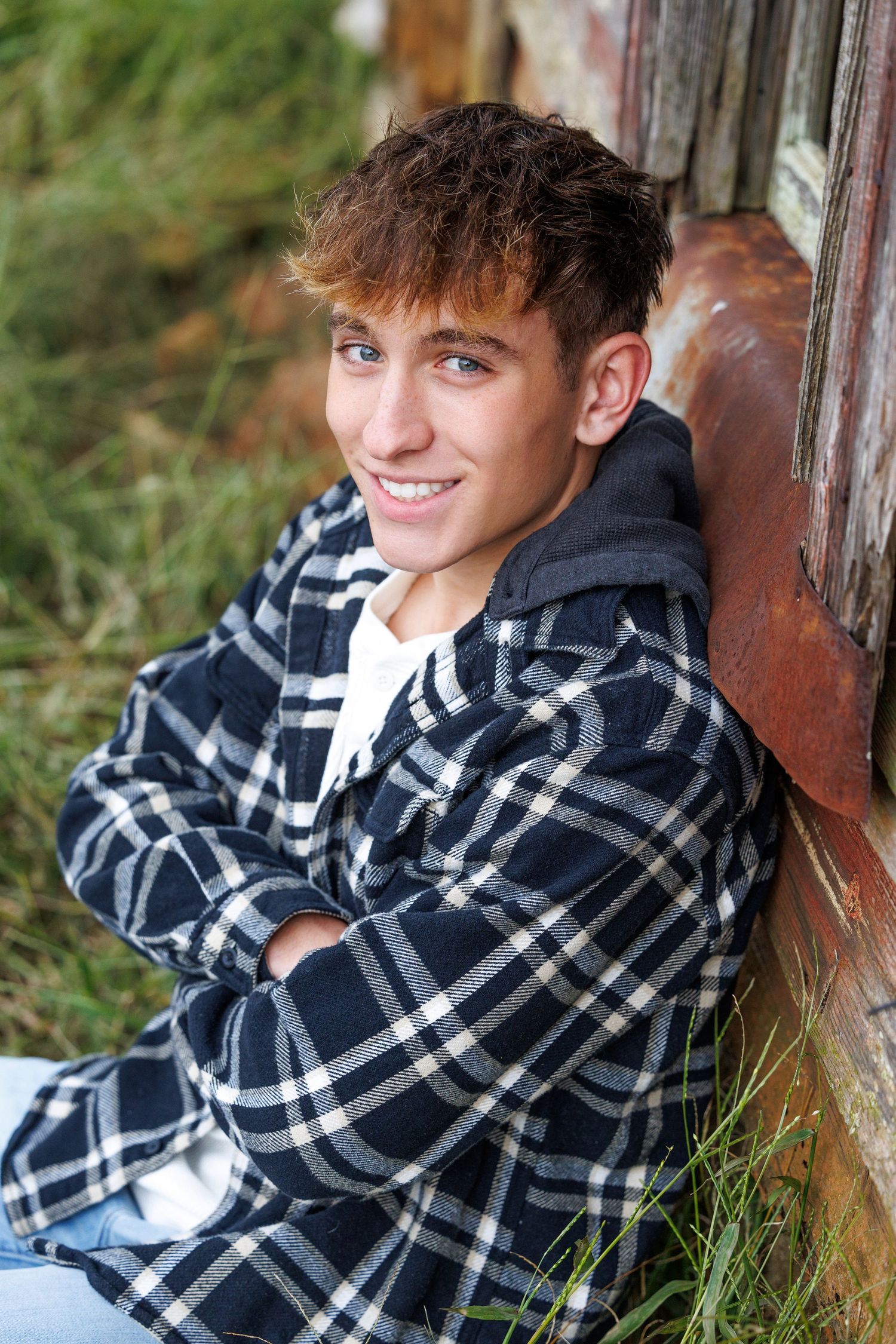 Senior Portrait of a boy in a plaid shirt. Casual senior pose of a boy smiling.