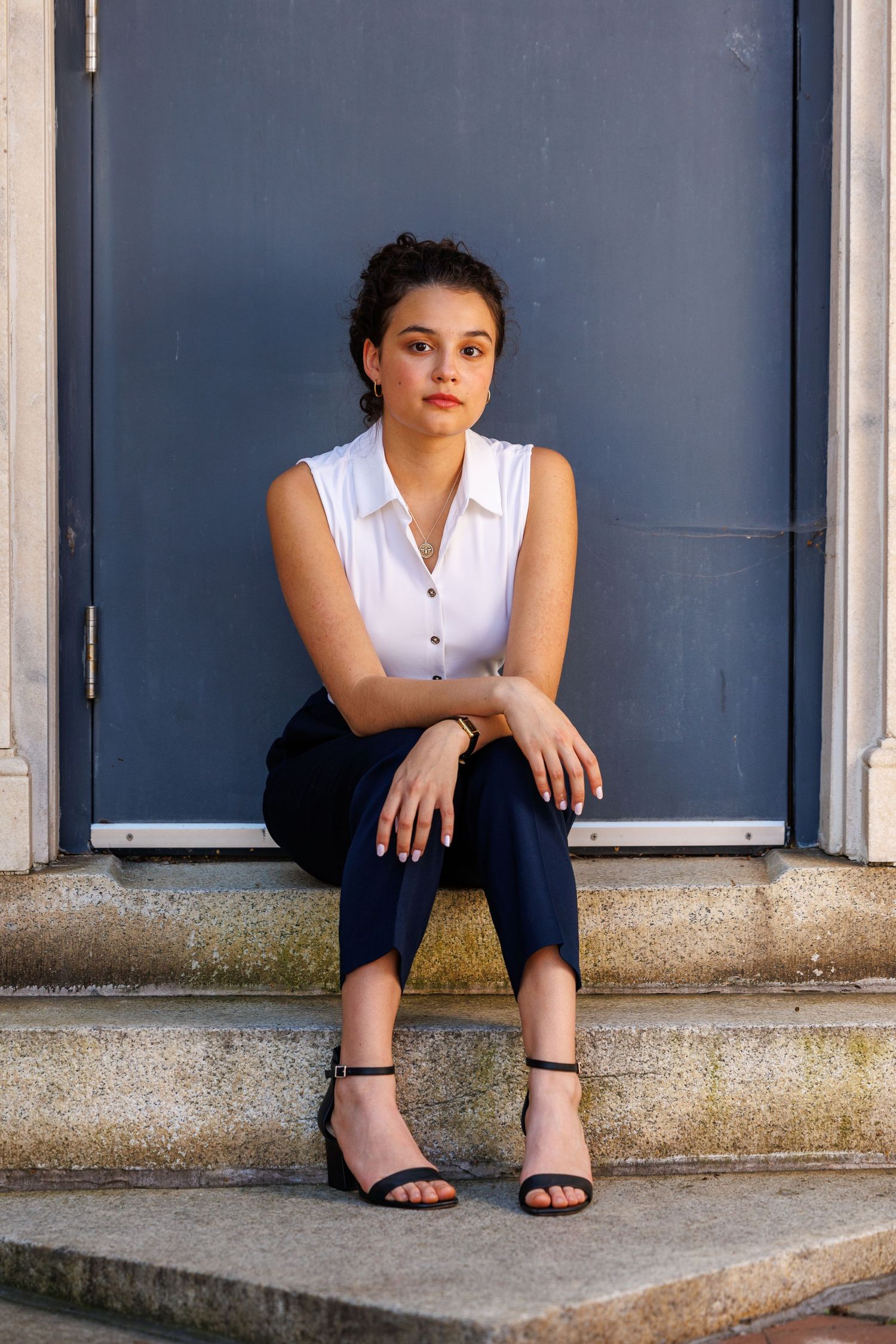 Casual business attire portrait on concrete steps against blue door.