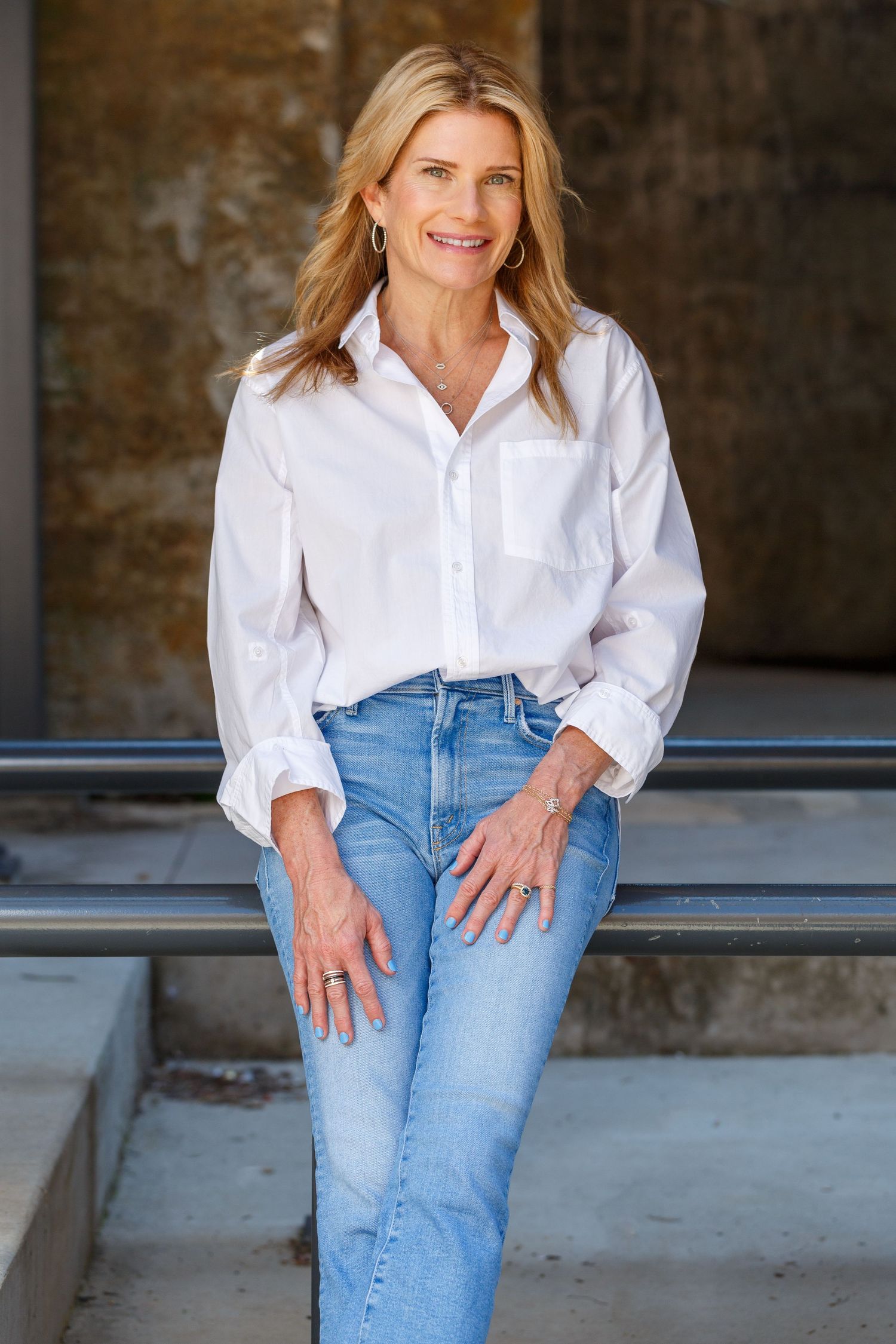 A casual outfit featuring a crisp white button-down shirt paired with light wash jeans in an urban setting.
