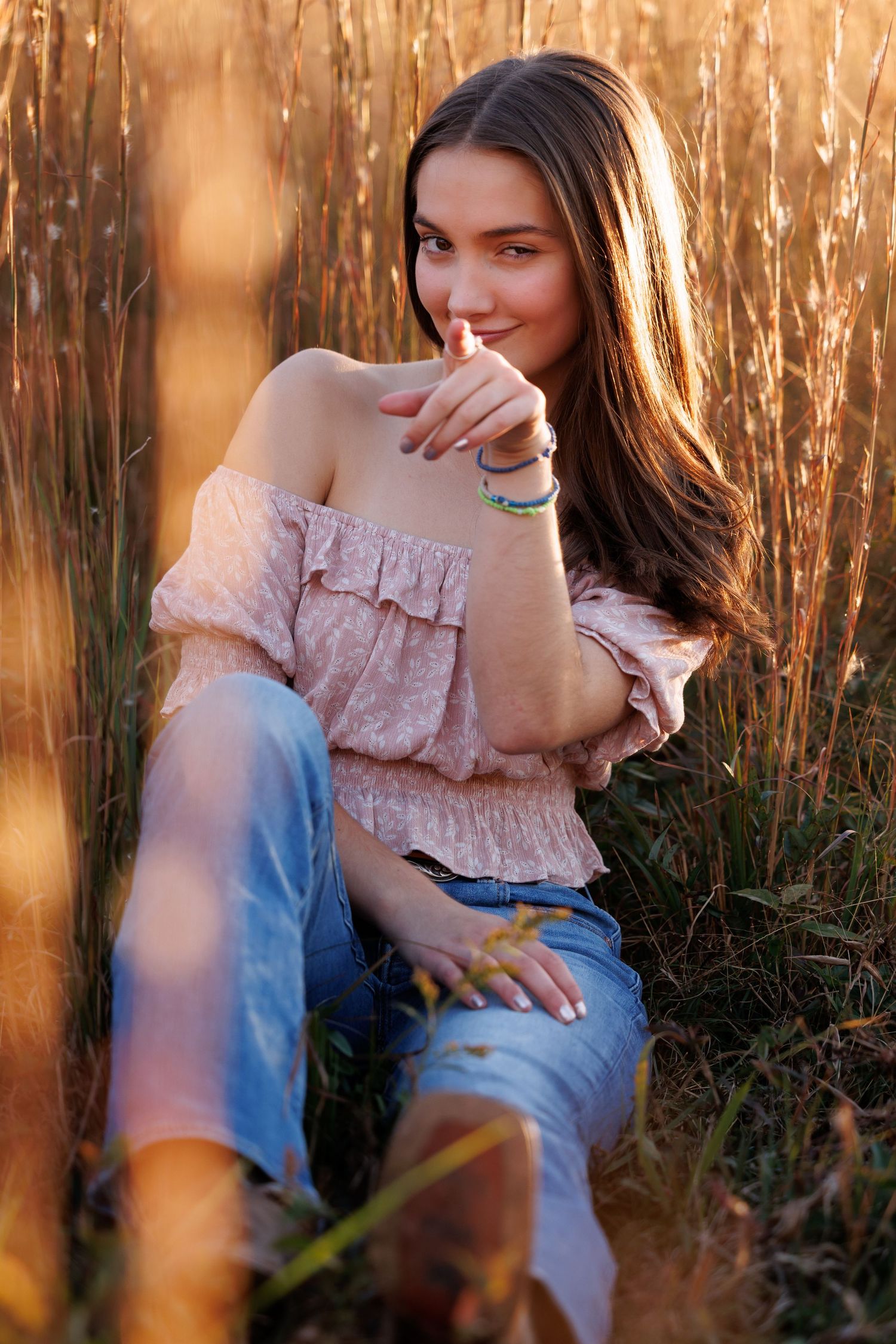 Stylish portrait in a golden wheatfield at sunset featuring casual off-shoulder top and jeans in warm lighting.