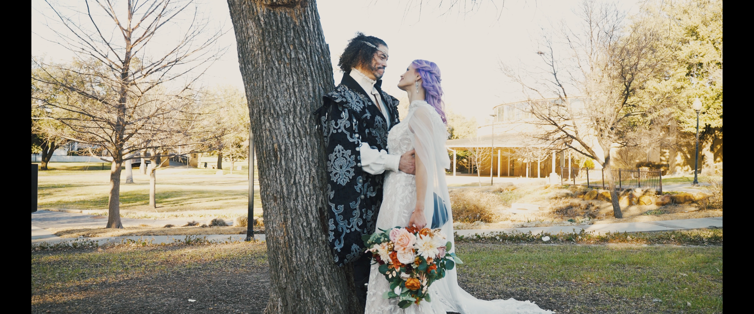 A couple dances together in an outdoor field, the bride wearing a flowing white gown.