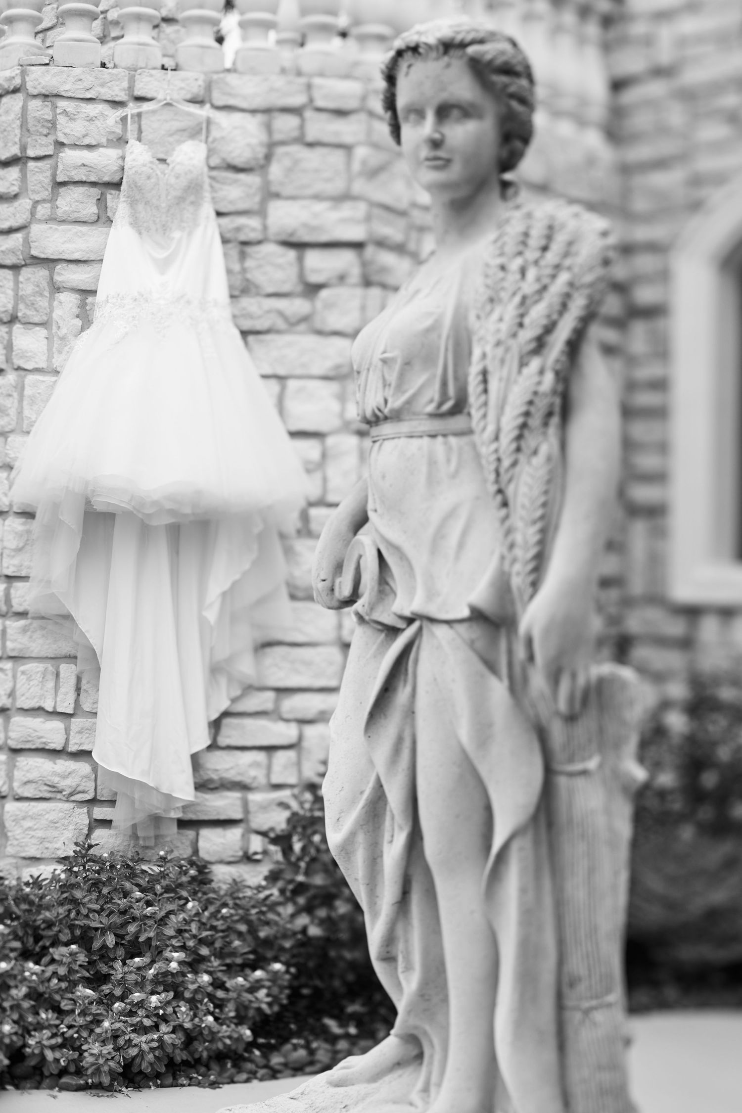 Artistic black and white photo of statues against stone brick wall.