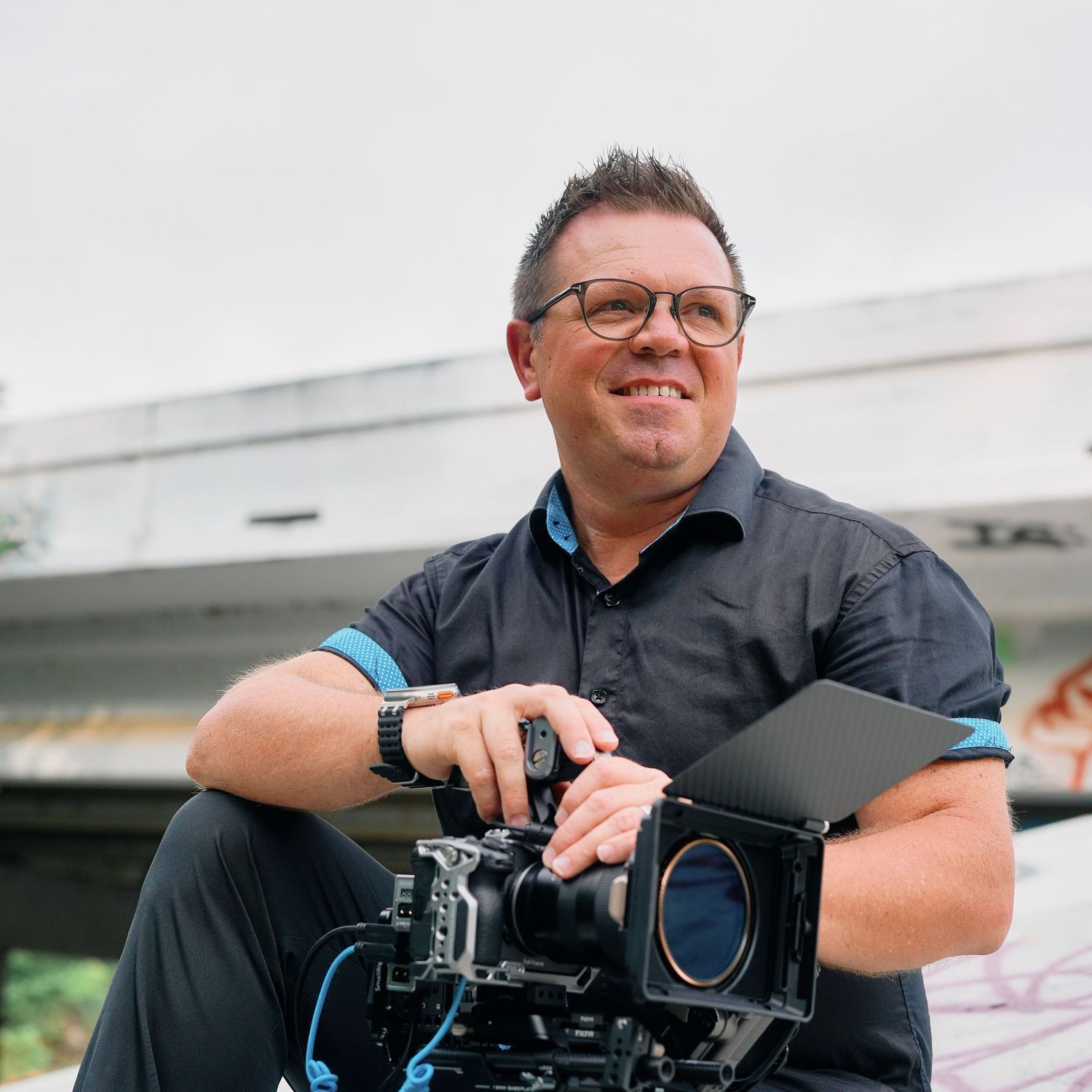 Professional photographer holds camera rig while working on set with production equipment.