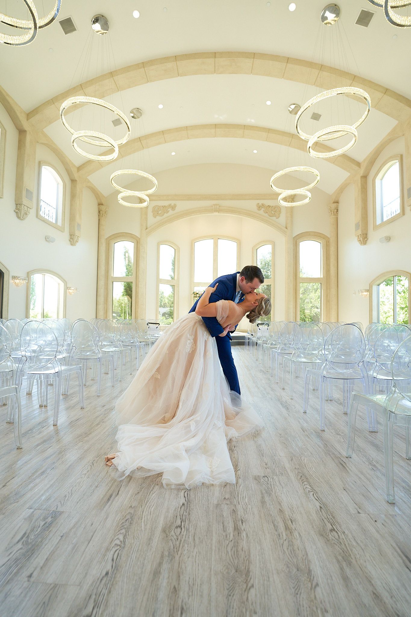 Wedding venue interior with modern circular lighting and rows of white chairs.
