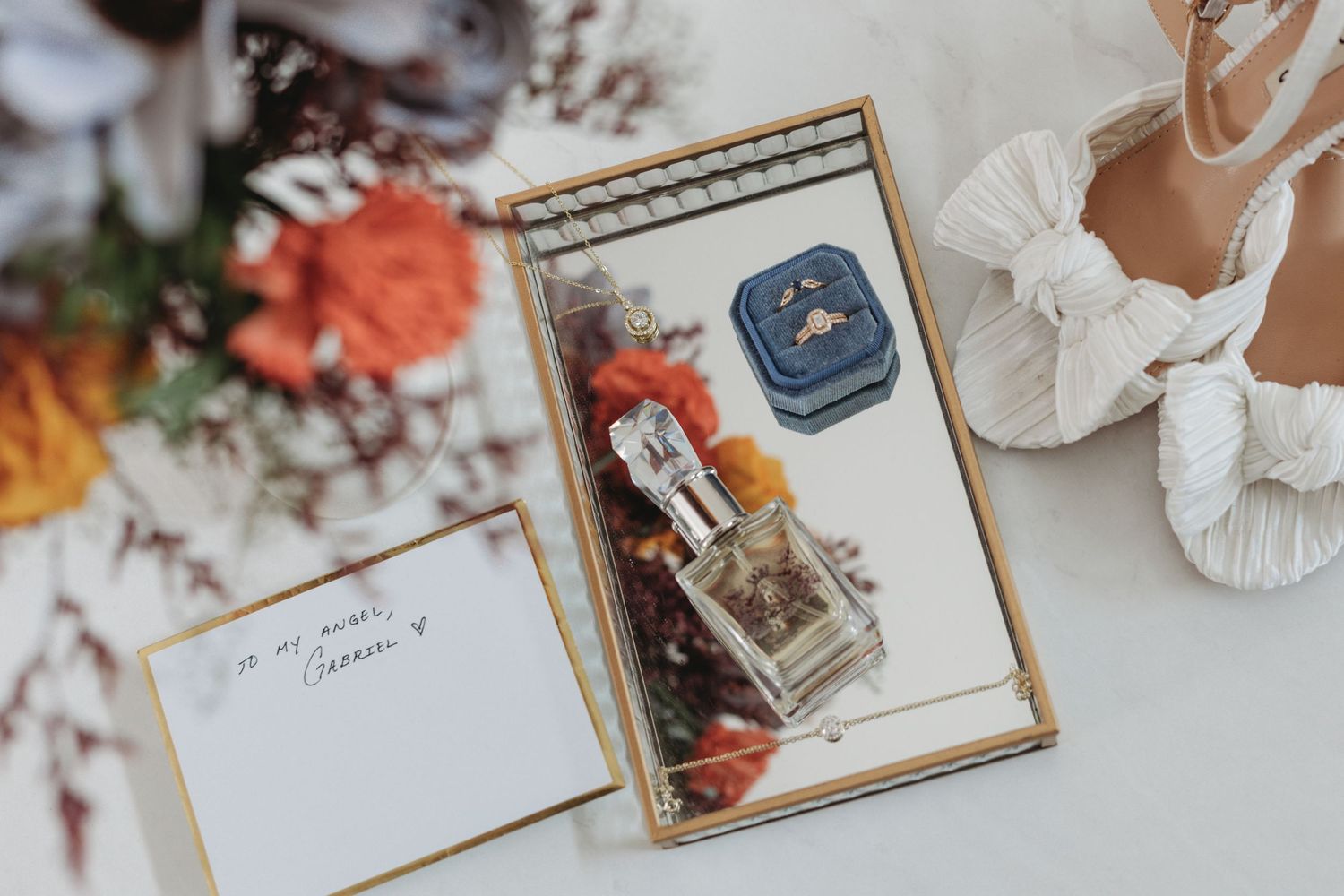 Elegant wedding details including floral arrangements and decorative cards laid out on a white surface.