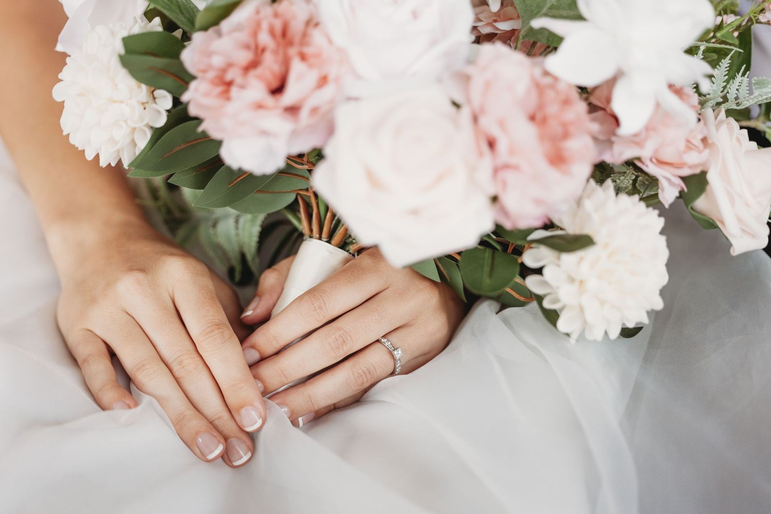 Delicate pink and white floral bouquet with green foliage against a light background.